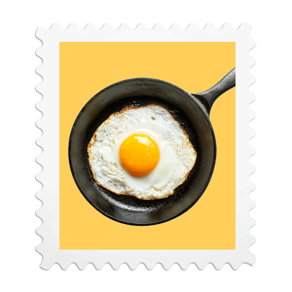 A fried egg sunny side up in a black skillet with a yellow background.