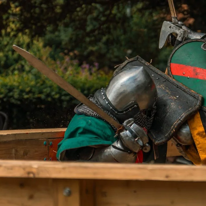 Close-up of a person in medieval armor riding a wooden cart, holding a sword