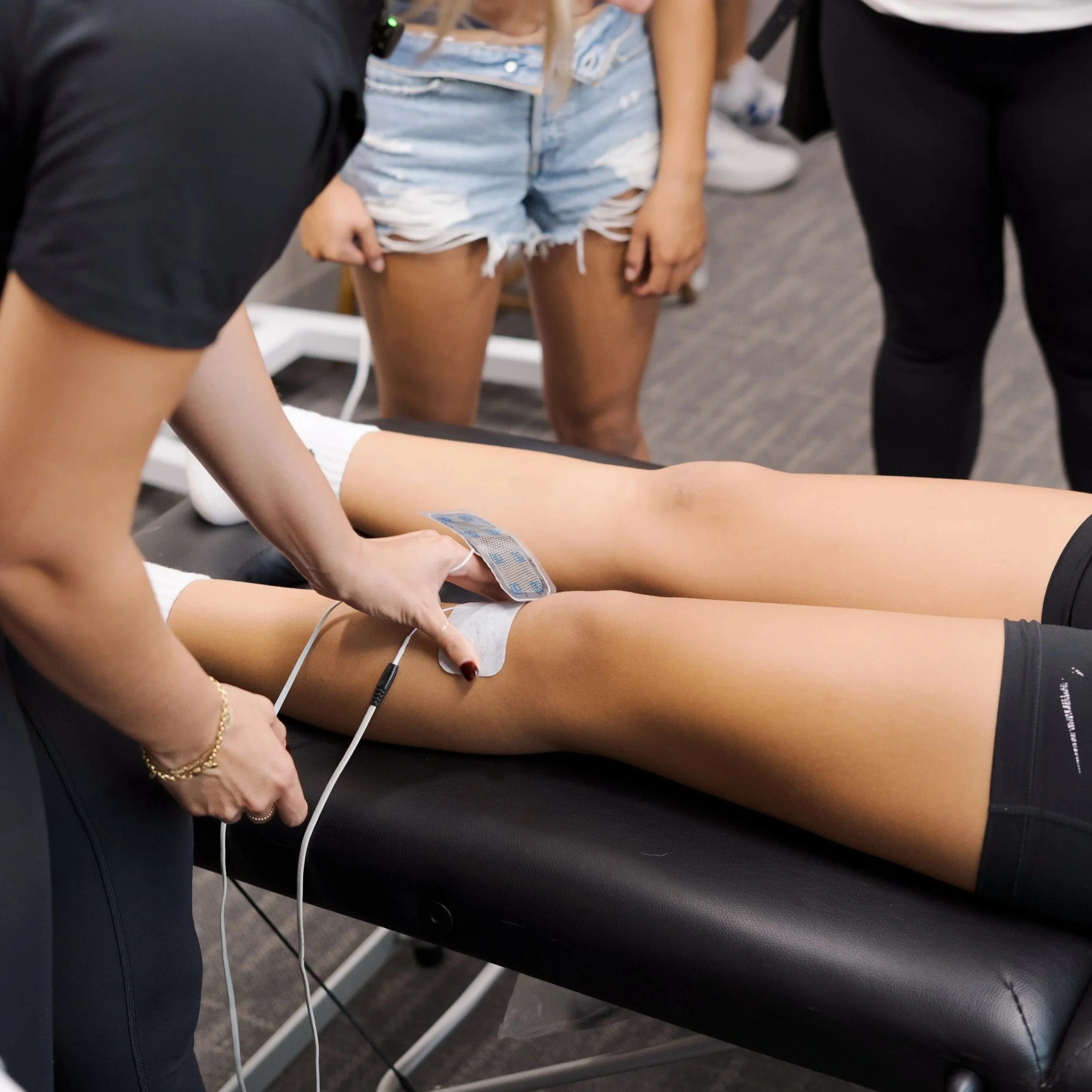 Dr. BettyLou DeYoung applying electrical stimulation (ARP Wave) therapy to a patient's knee at Rise & Reframe Physical Therapy in Temecula, CA — a hands-on recovery technique used to reduce pain and support tissue healing
