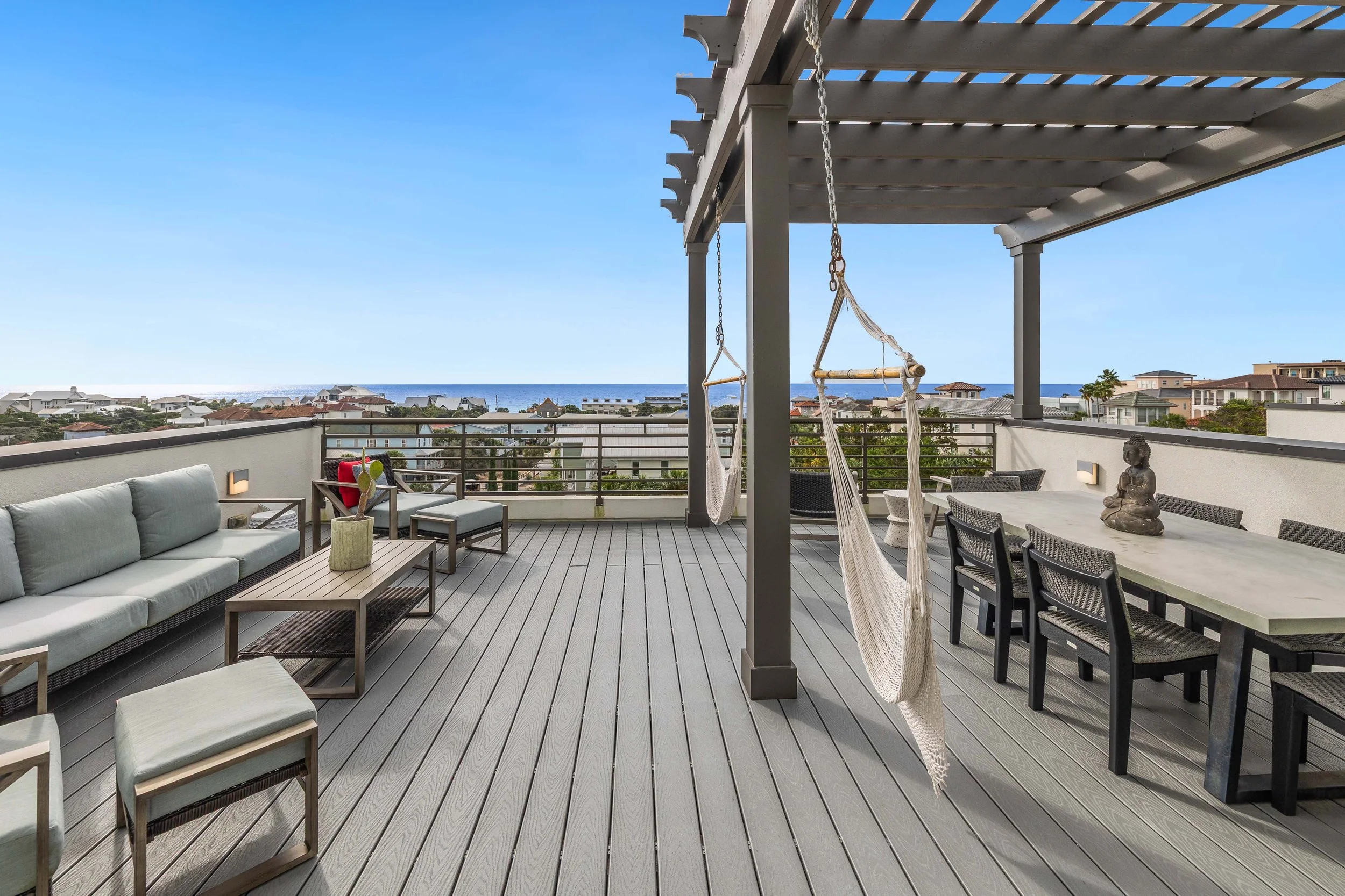 Rooftop living space complete with sofas, chairs, two swings and a dining area.