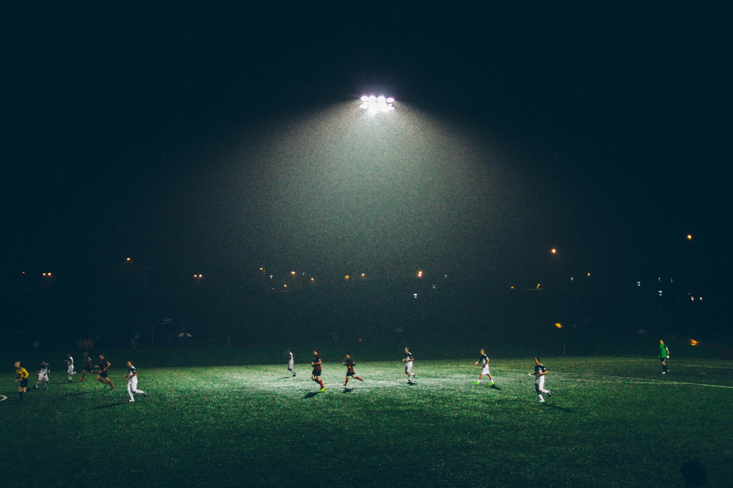 A soccer match being played under floodlights at night, with players on the field.