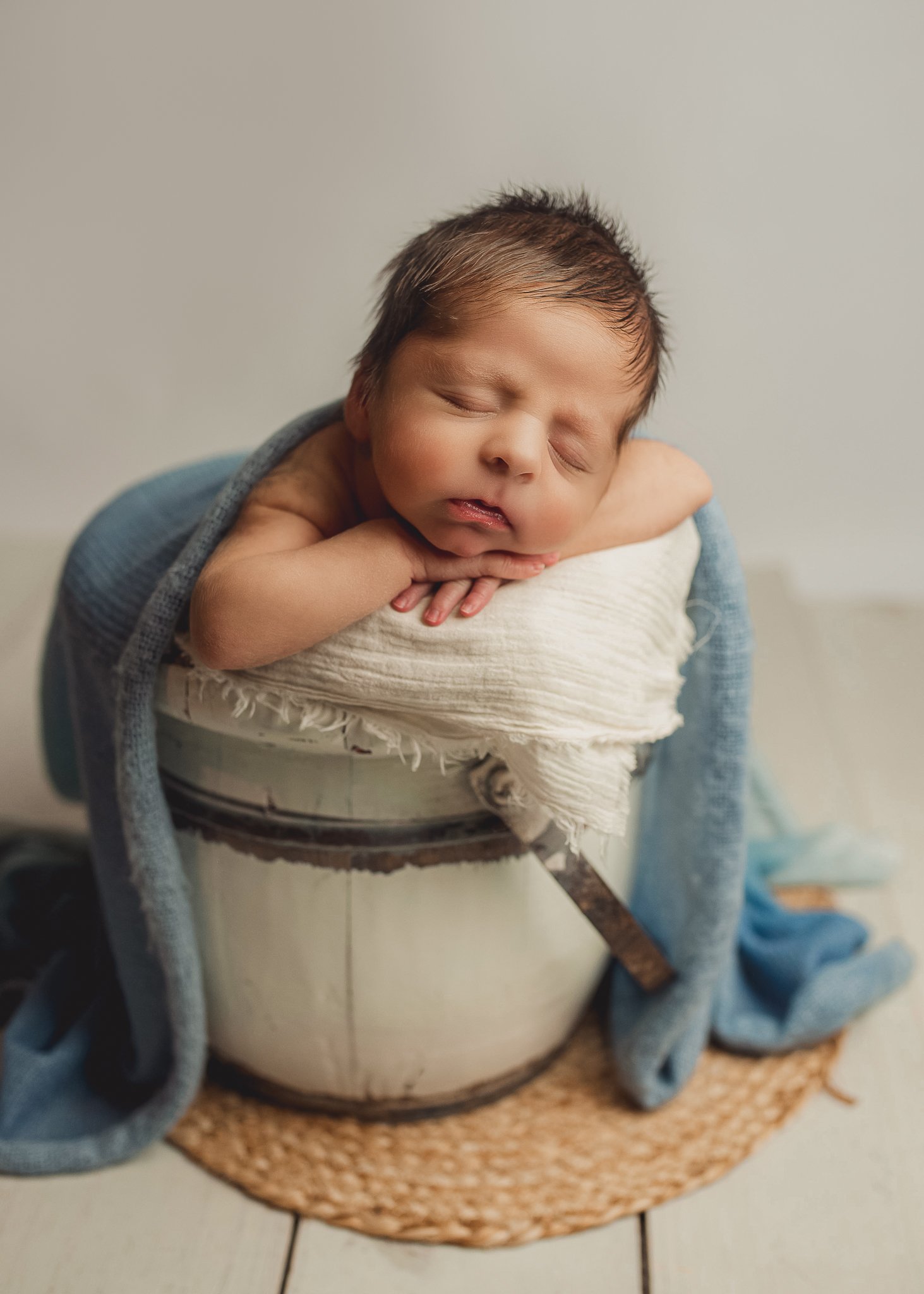 Sleeping newborn baby wrapped in blue during a posed newborn photography session.
