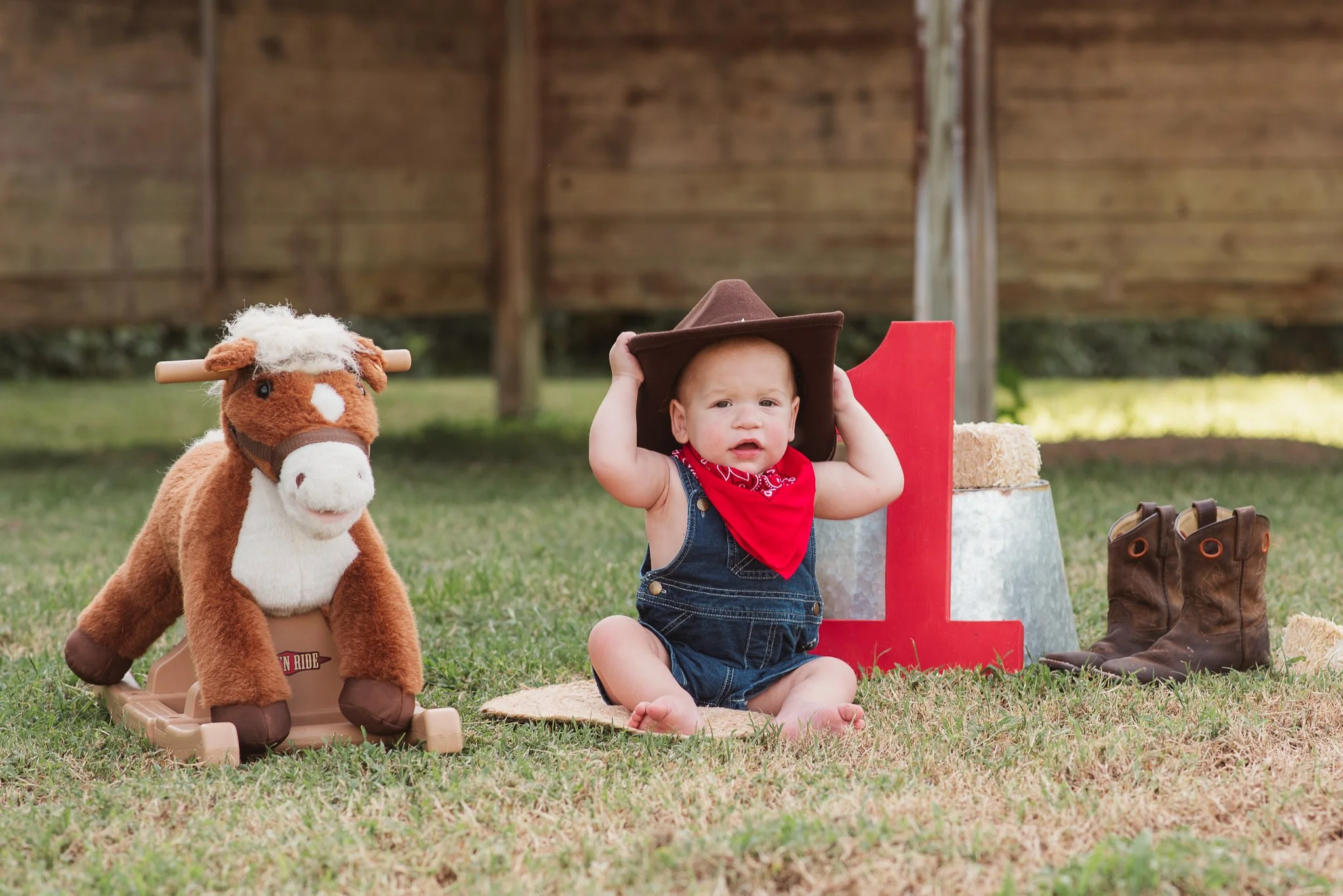 Baby in a cowboy themed setup during an outdoor first birthday photography session.