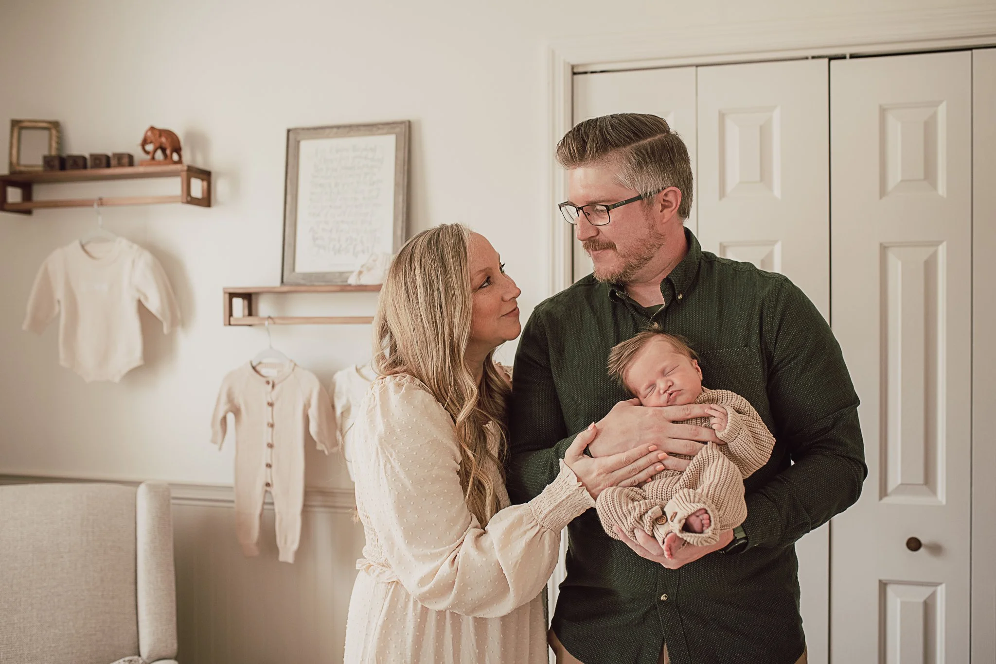 Parents holding their newborn baby in the nursery during an in-home lifestyle newborn photography session.