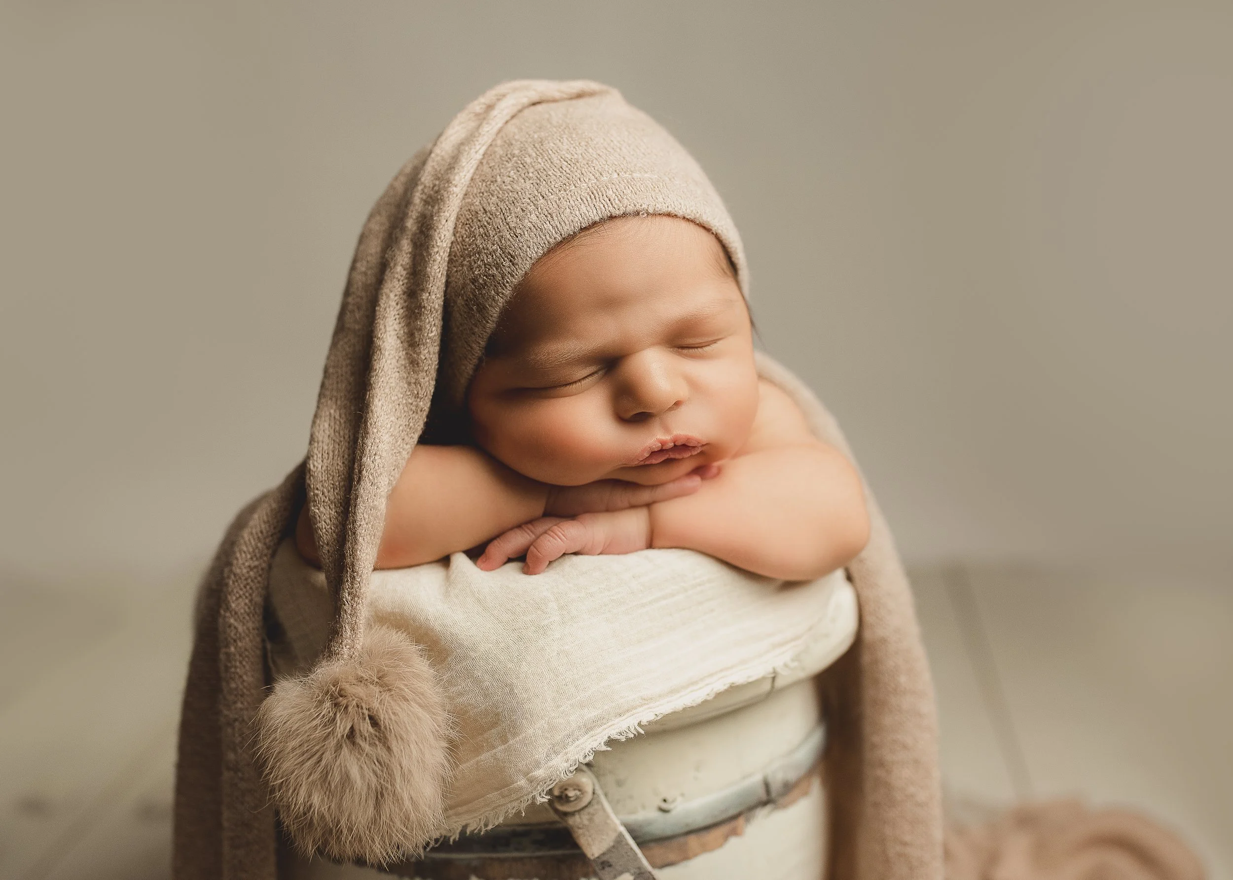 Sleeping newborn baby posed in soft neutral tones during a newborn photography session.