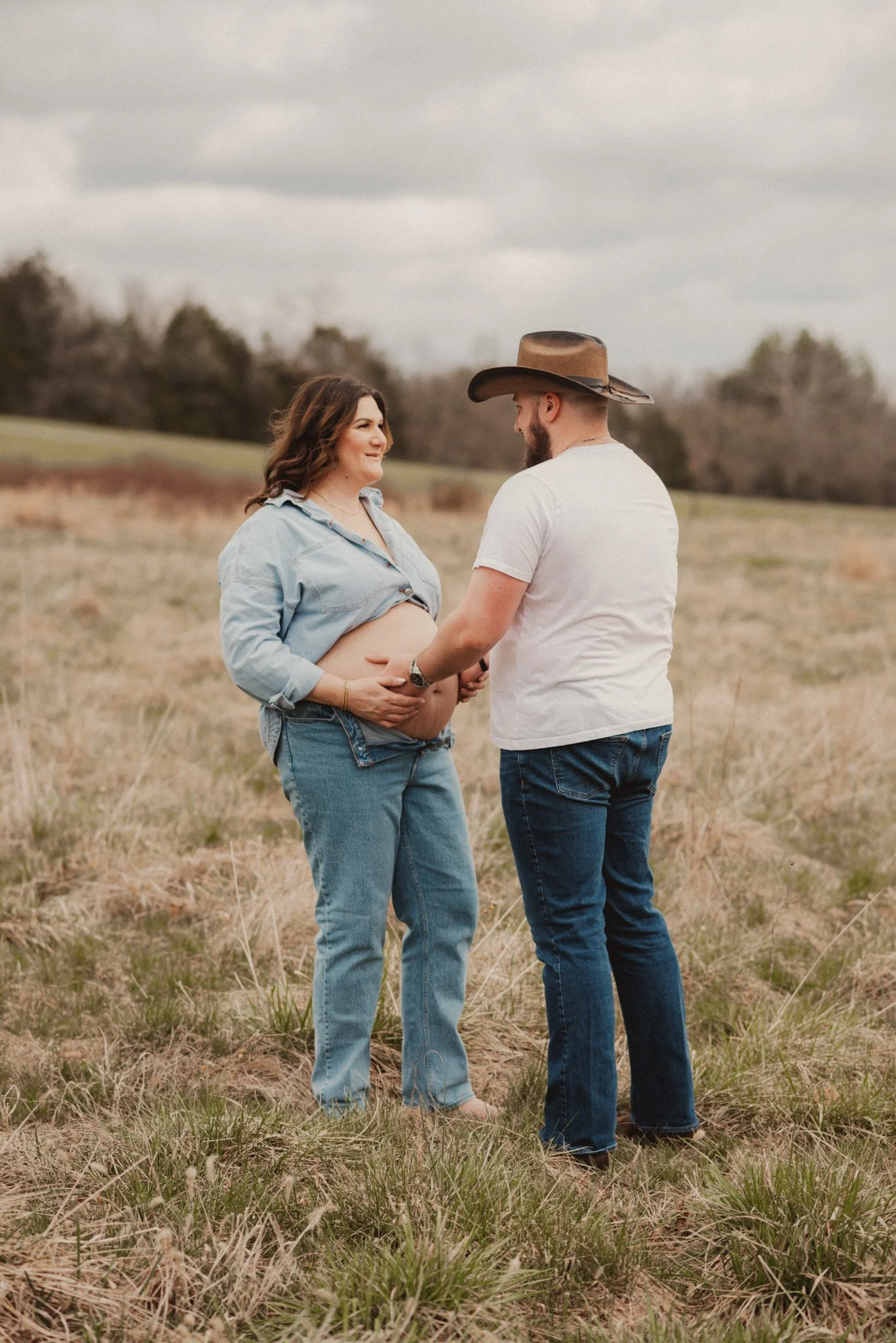 Expecting parents together in a field during an outdoor maternity photography session.