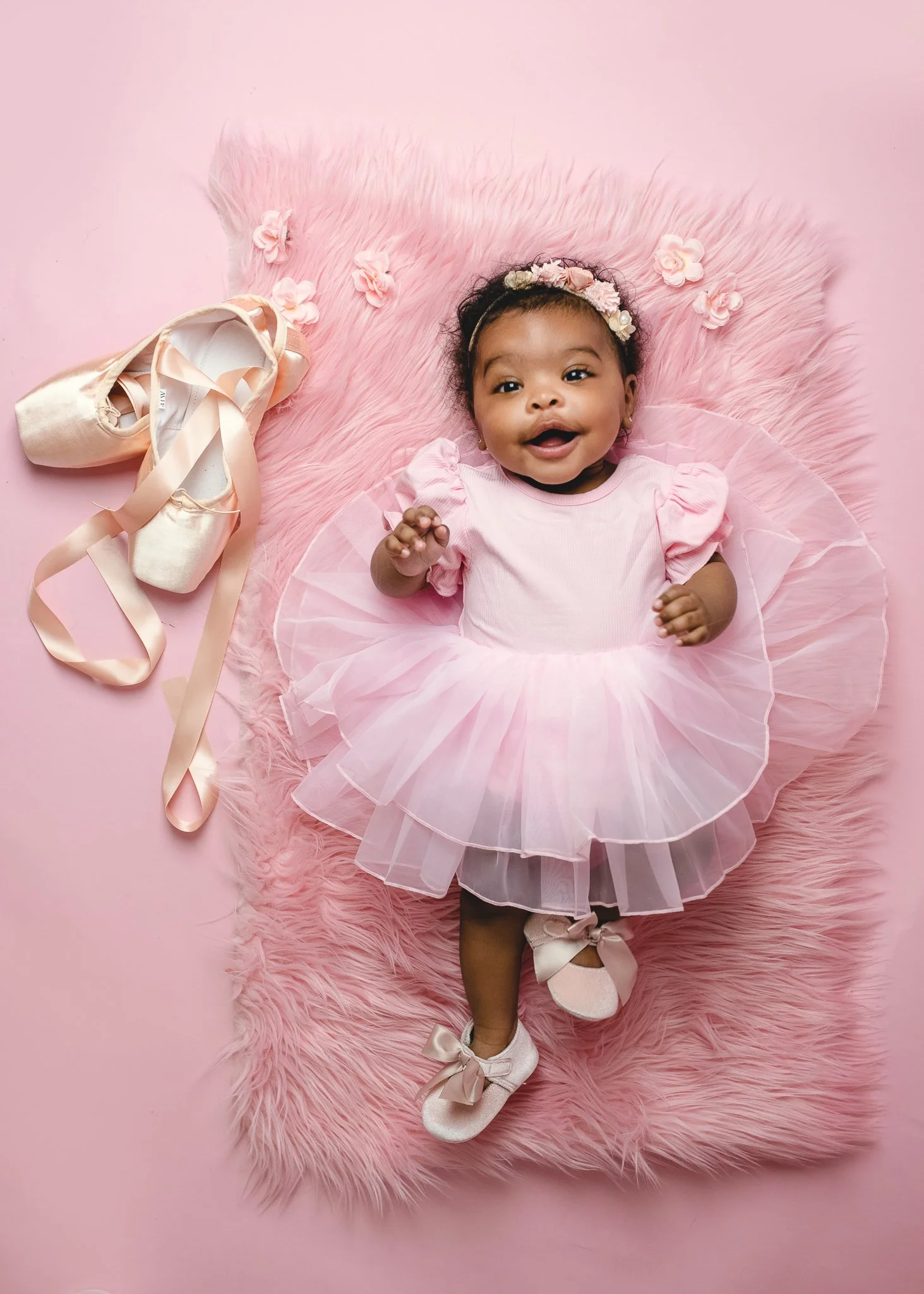 Baby girl in a pink ballerina themed setup during a milestone photography session.