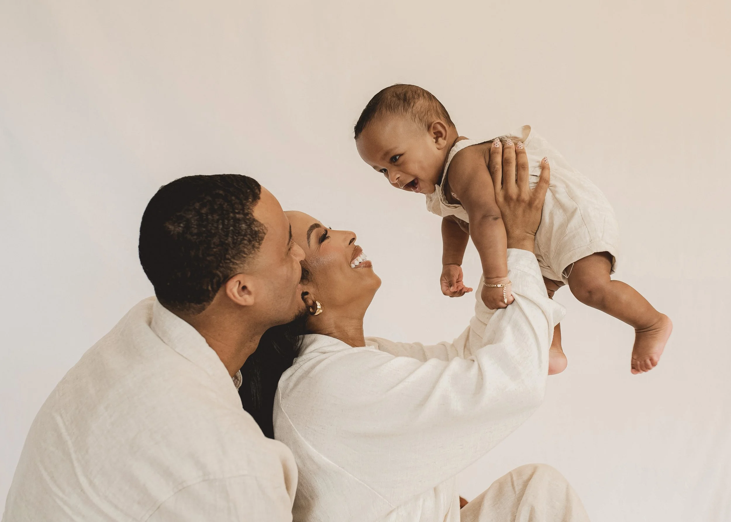 Parents playing with their baby during a relaxed studio family photography session.