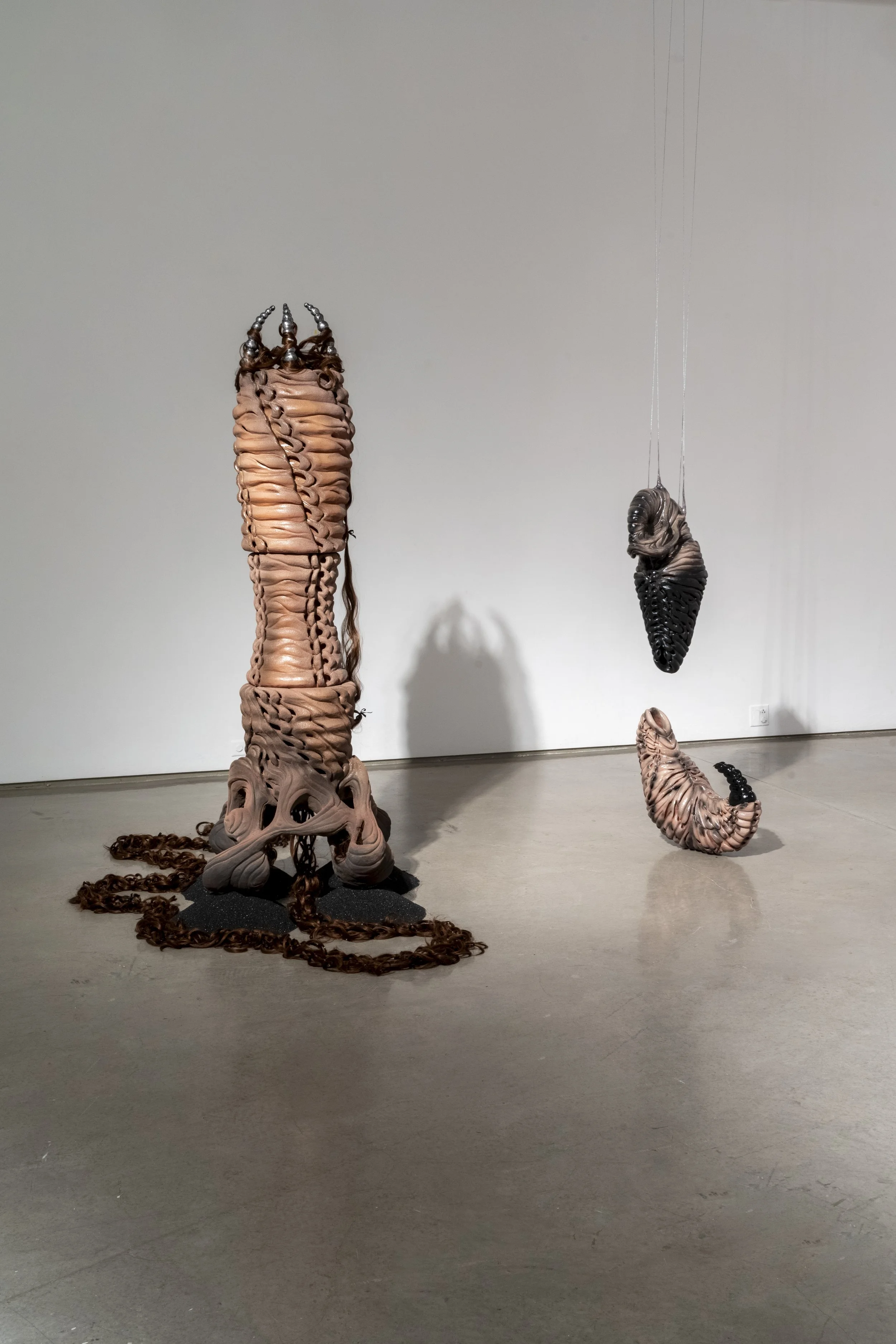 Installation view of: ant/i/bodies, 2025. Ceramic, cast aluminum, synthetic hair, sand blasting medium, polyester ribbon, beeswax, human hair, rubber, silicone, acrylic nails. Various dimensions.