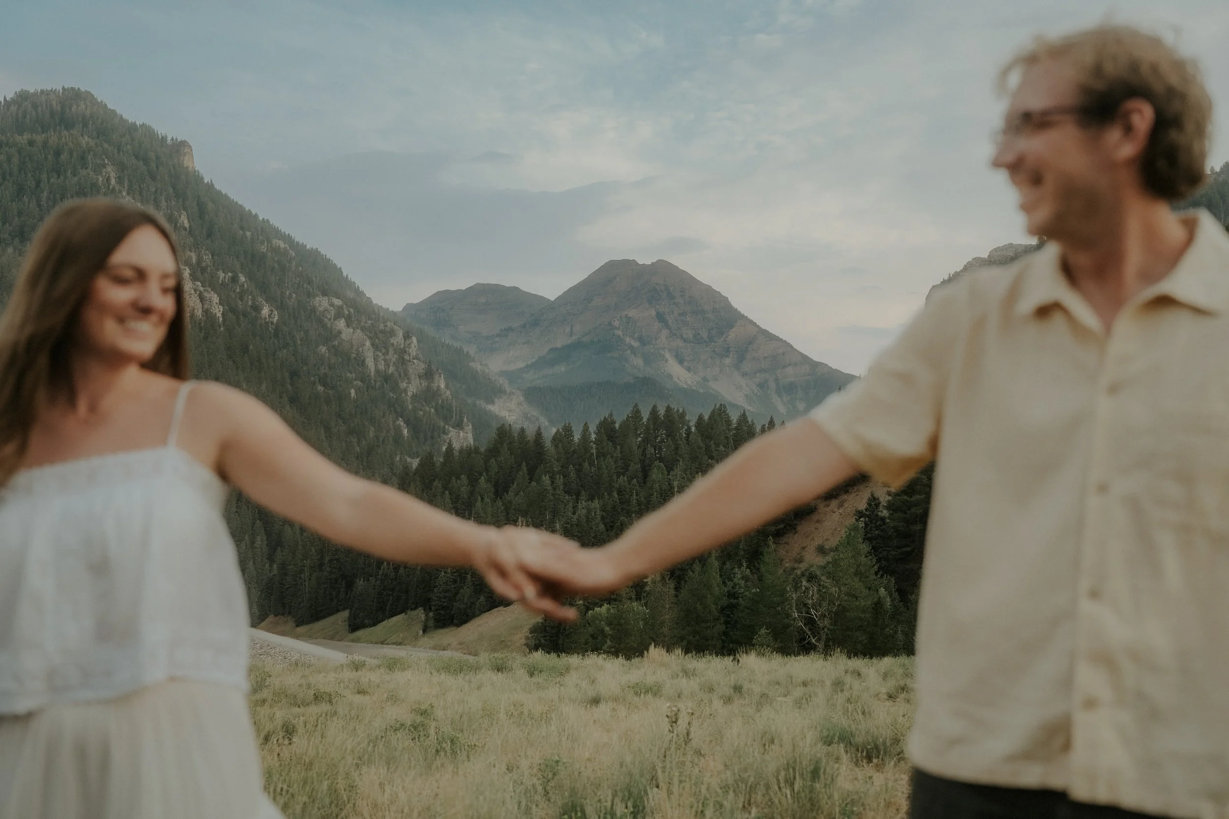 Two people holding hands stretched out in front of a mountain view.