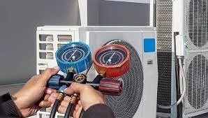 Person holding set of manifold gauges connected to a portable air conditioning unit.