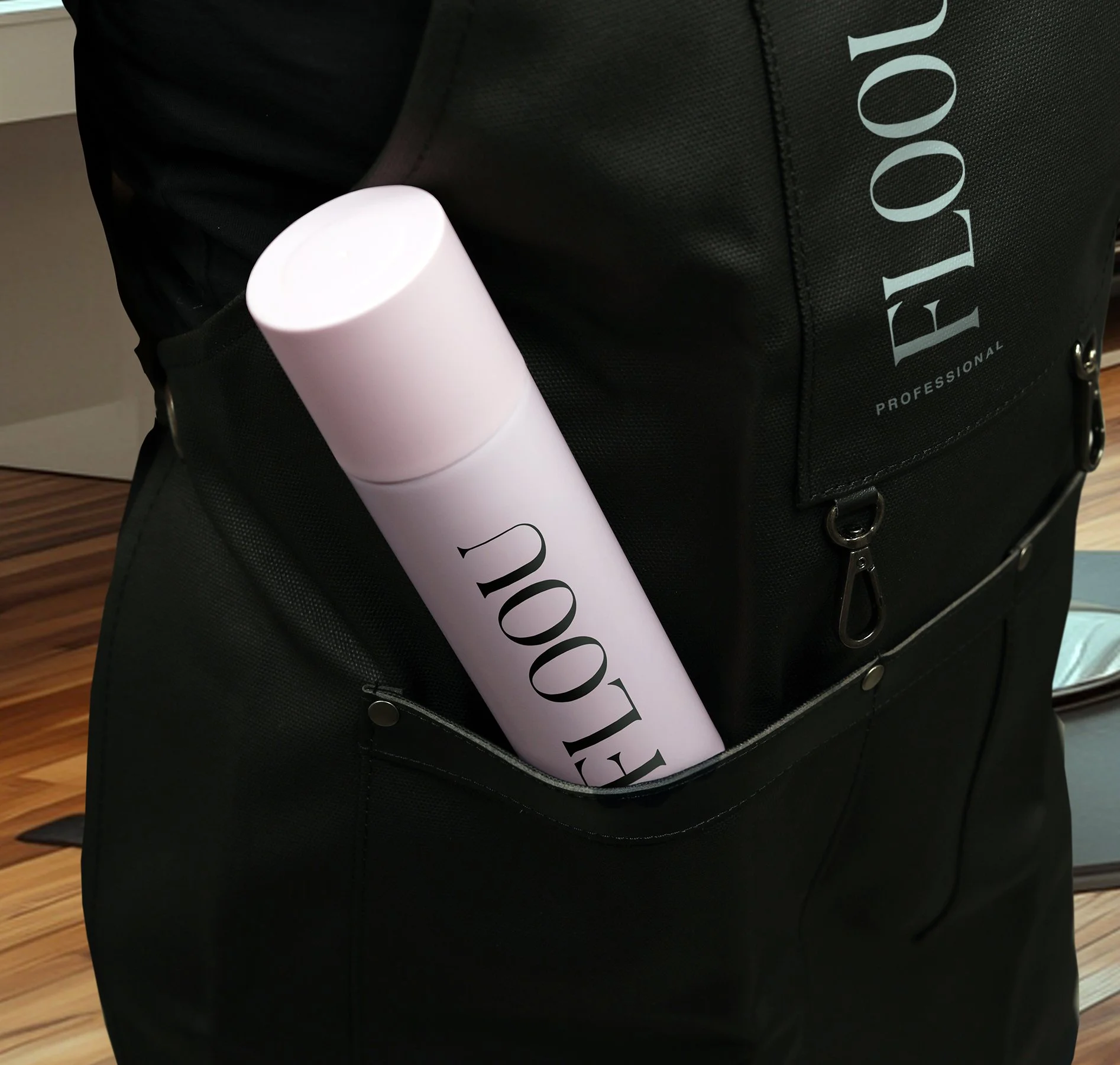 Musta essu ja hiuslakkapullo, jossa lukee FLOOU