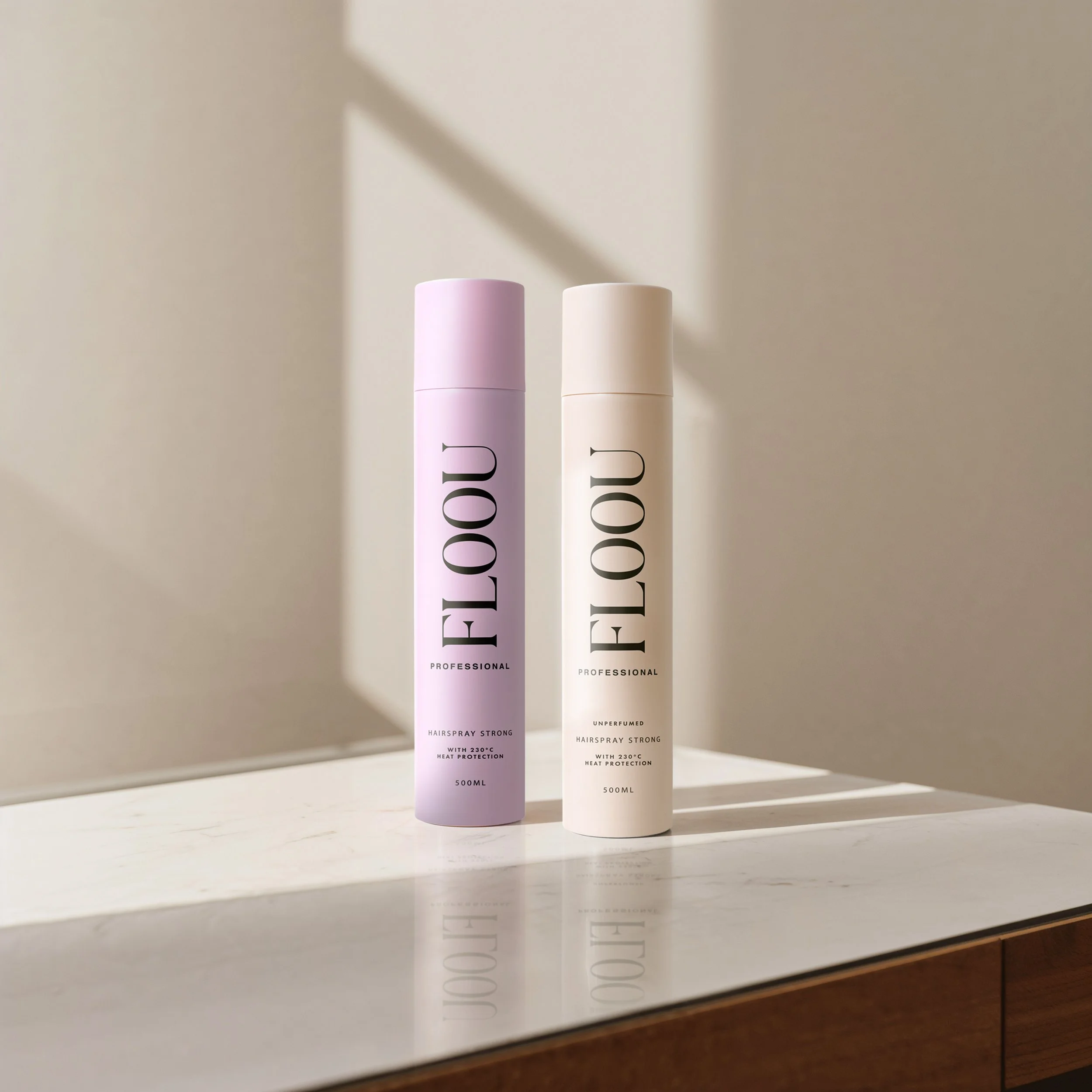 Kaksi hiuslakkapulloa, toinen vaaleanpunainen ja toinen valkoinen, asettuna valkoiselle tasolle seinää vasten, joissa on tekstit "FLOOU" ja "PROFESSIONAL".