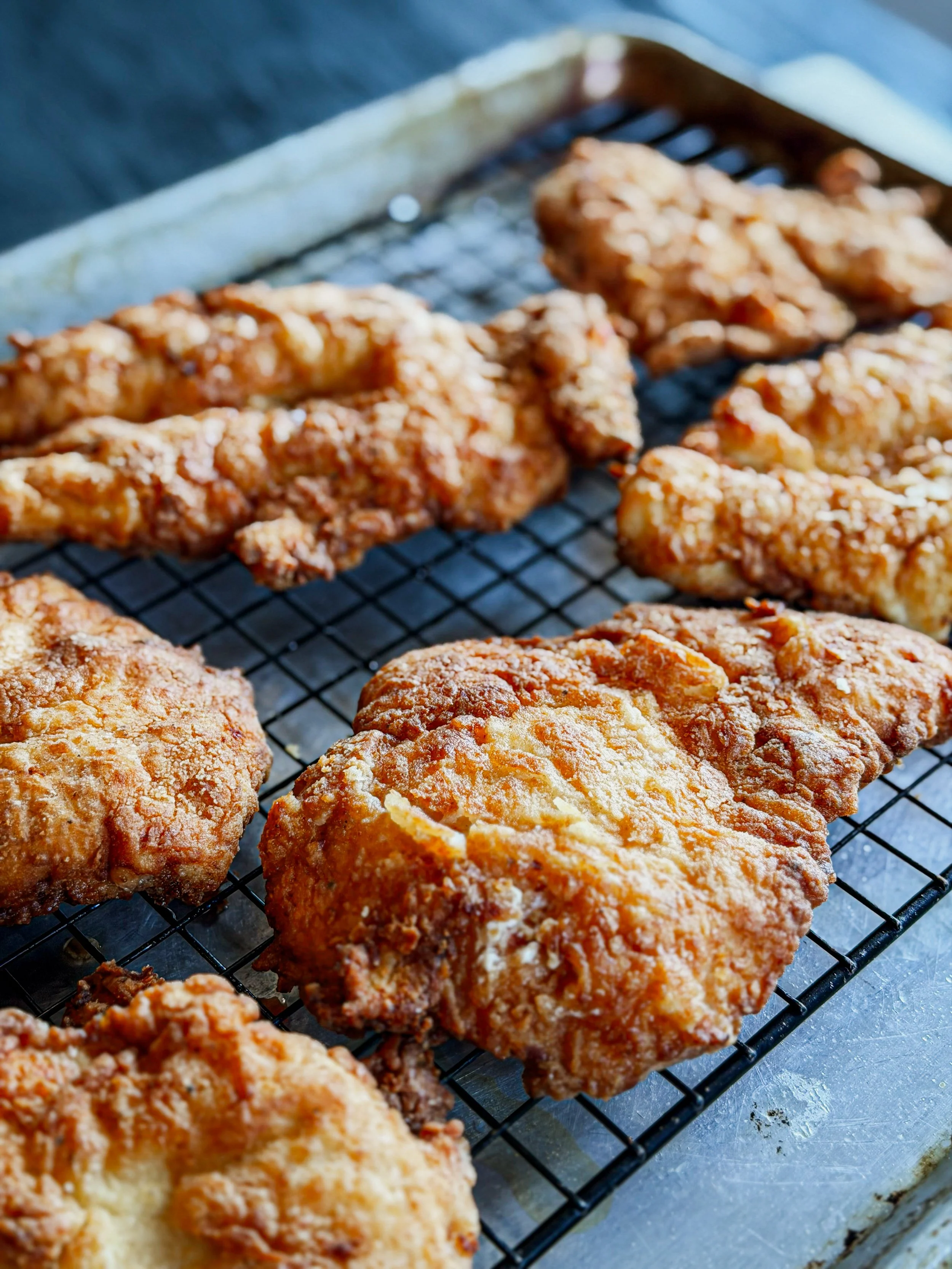Fried chicken on a wire rack with a crispy, golden-brown coating.
