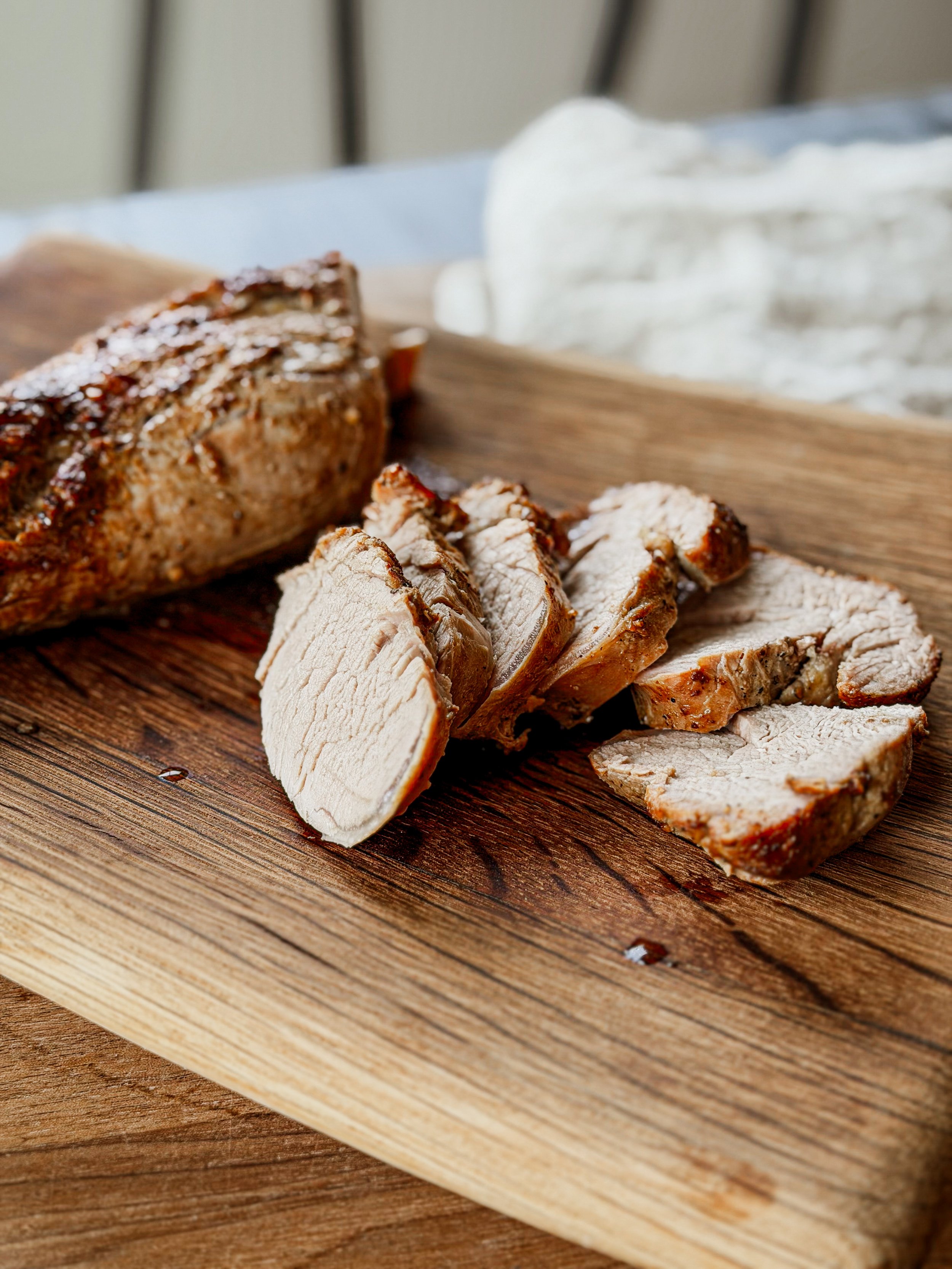 Slices of cooked turkey breast on a wooden cutting board with a snowball and blurred background.