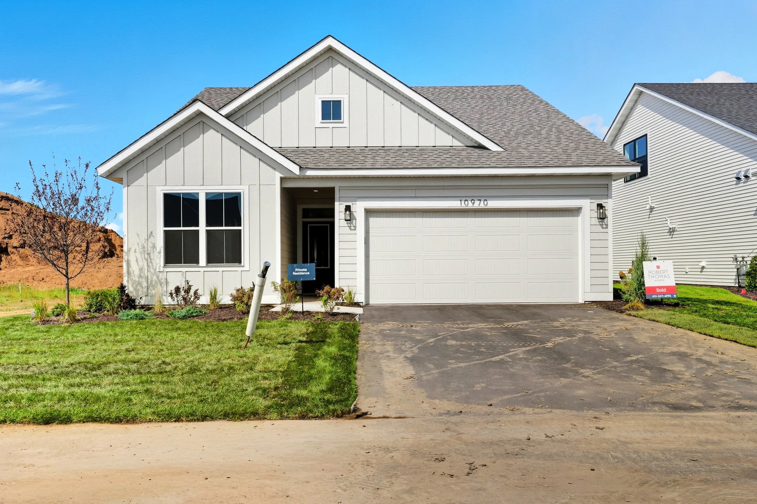 Newly built two-story house with white exterior, attached garage, small front lawn, and a