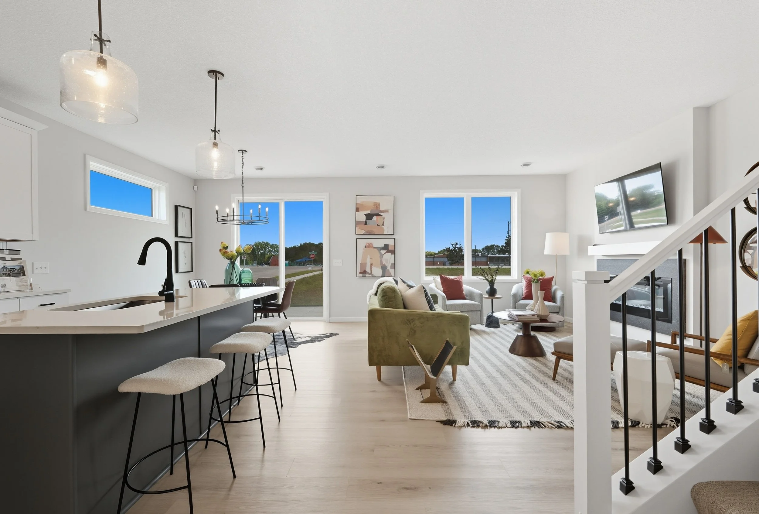 Open living room and kitchen area with large windows, modern furniture, and a fireplace.