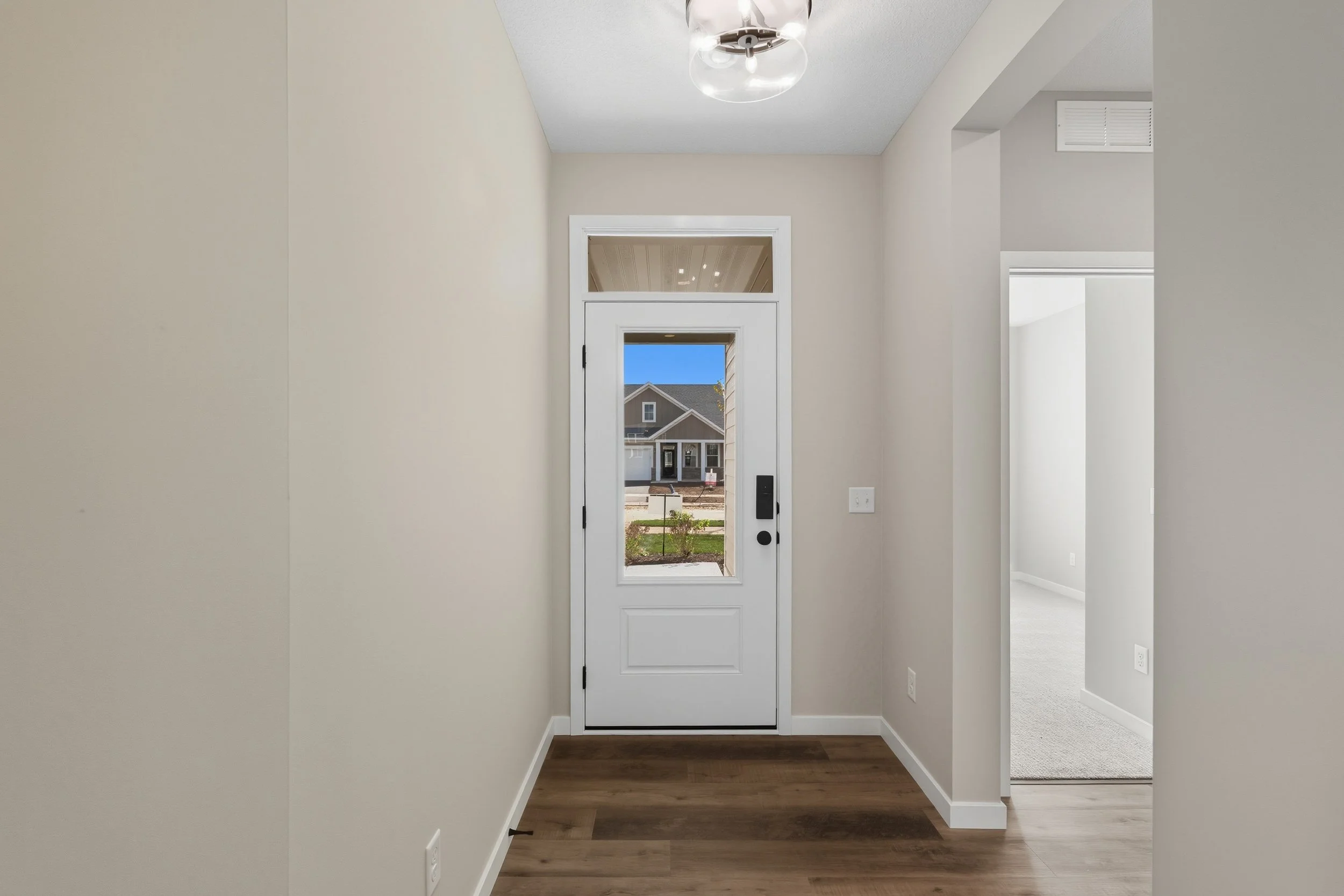 Interior view of a front door in a modern house, with a glimpse of the street outside and a house across the road.