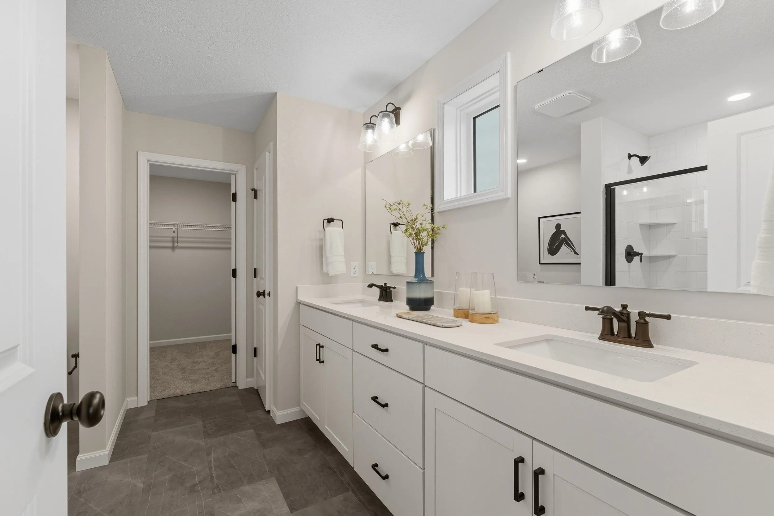 Modern bathroom with white vanity, large mirror, black fixtures, and a shower with glass door in the background.