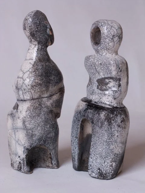 Two abstract ceramic sculptures with cracked glaze, featuring hollow and solid parts, positioned against a plain background.