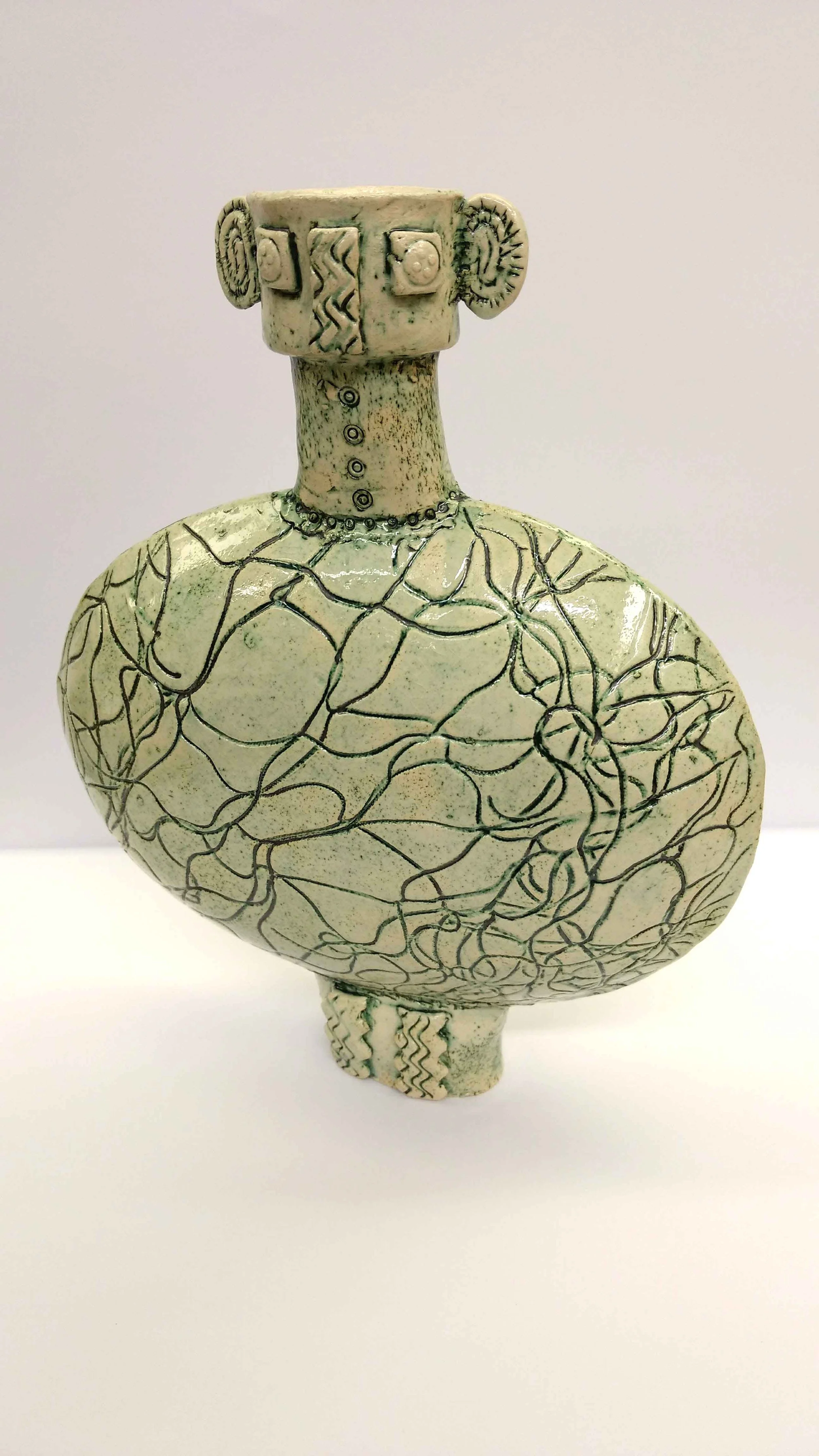 Ceramic sculpture of a human figure with a large, rounded body and a rectangular head, decorated with geometric and abstract patterns, against a plain white background.