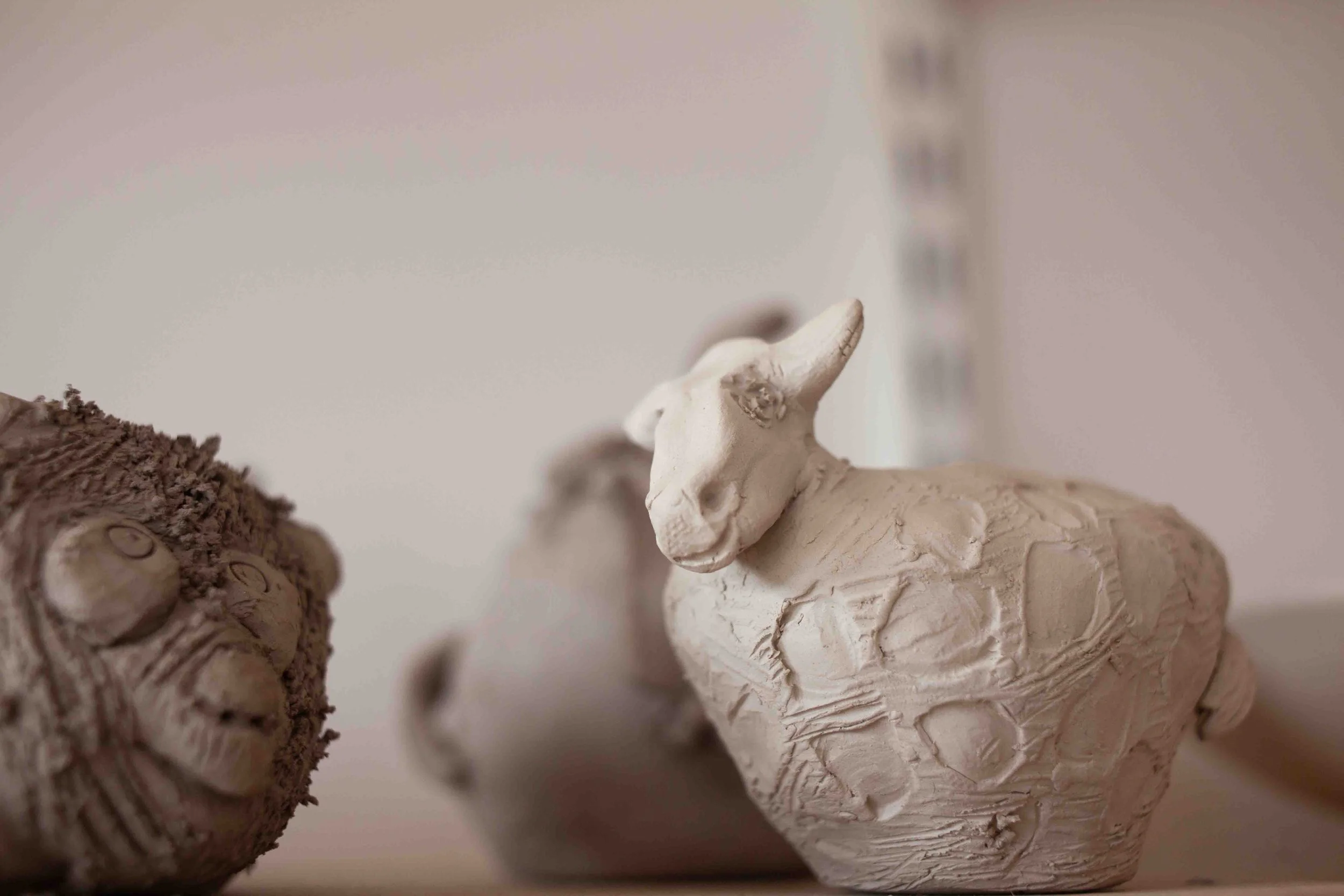 Close-up of a small, detailed ceramic or clay sculpture of a rabbit with textured fur and upright ears, from pottery classes