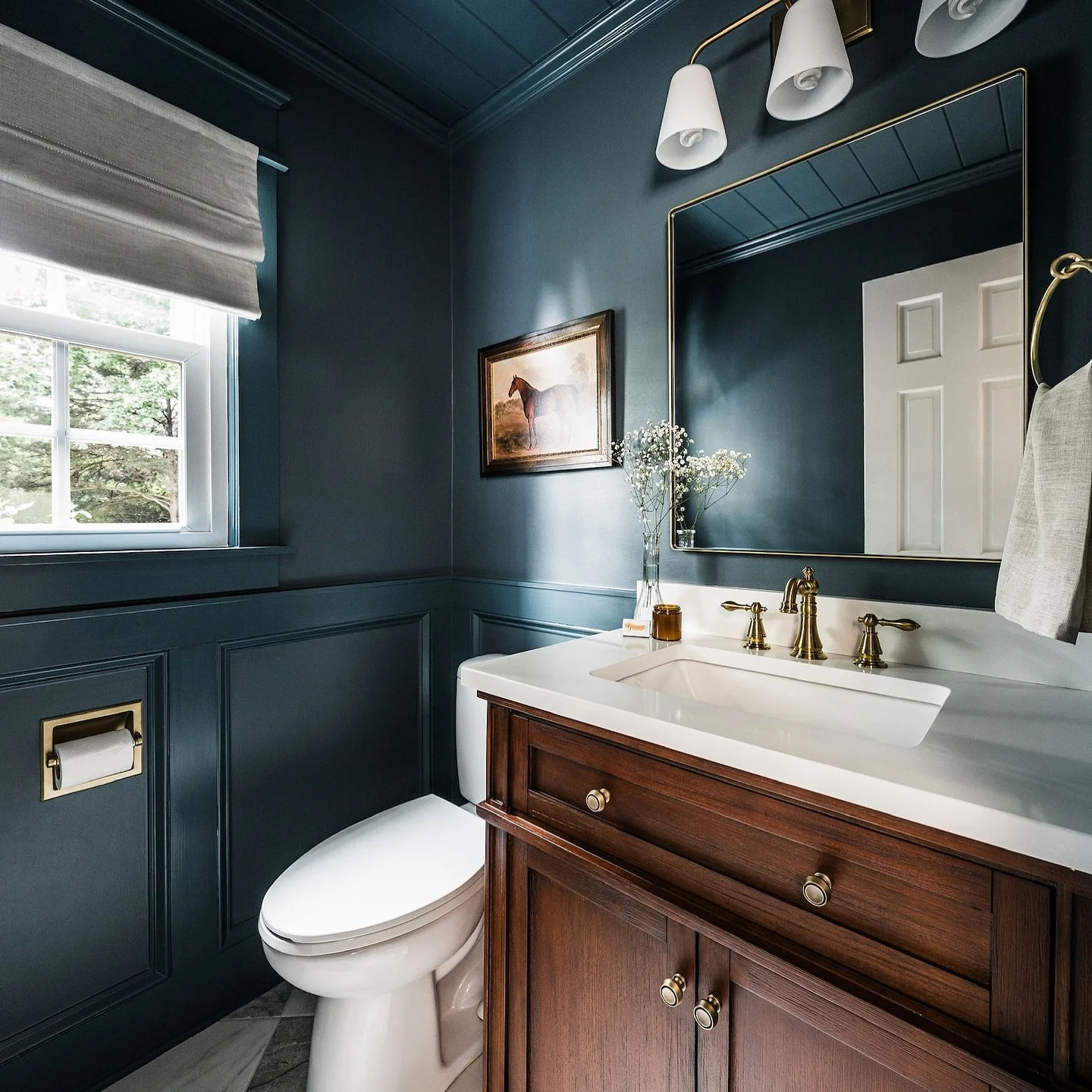 Moody. Sophisticated. Wrapped in rich blue from ceiling to trim. This powder bath proves that small spaces are the perfect place to go bold. Warm wood tones, brass accents, and a floor that bring the texture + contrast that make this room feel luxuri