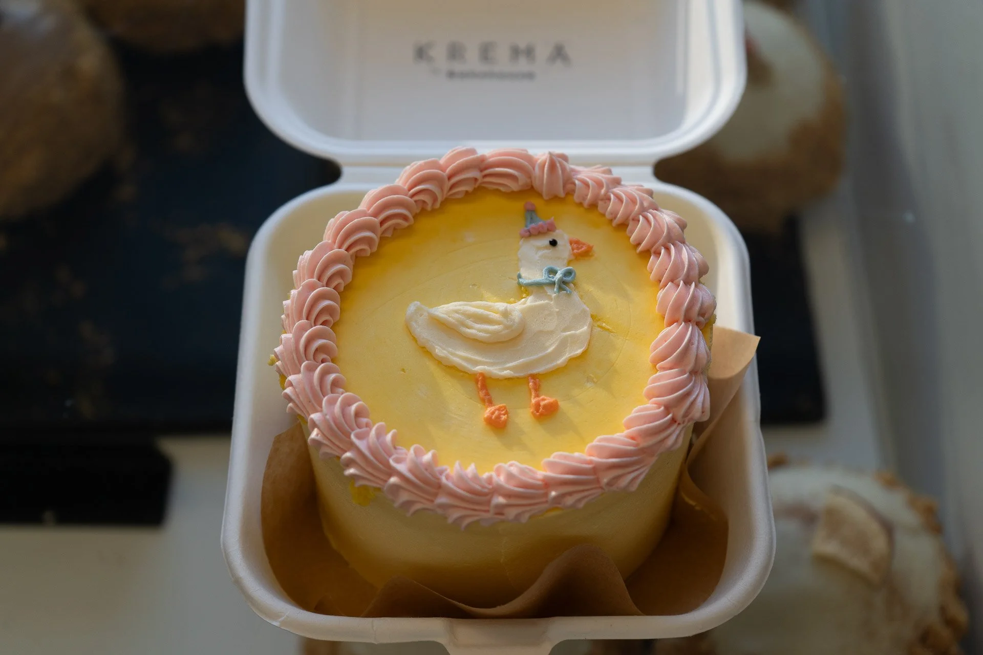Yellow cake with pink frosting border and a piped unicorn decoration on top.