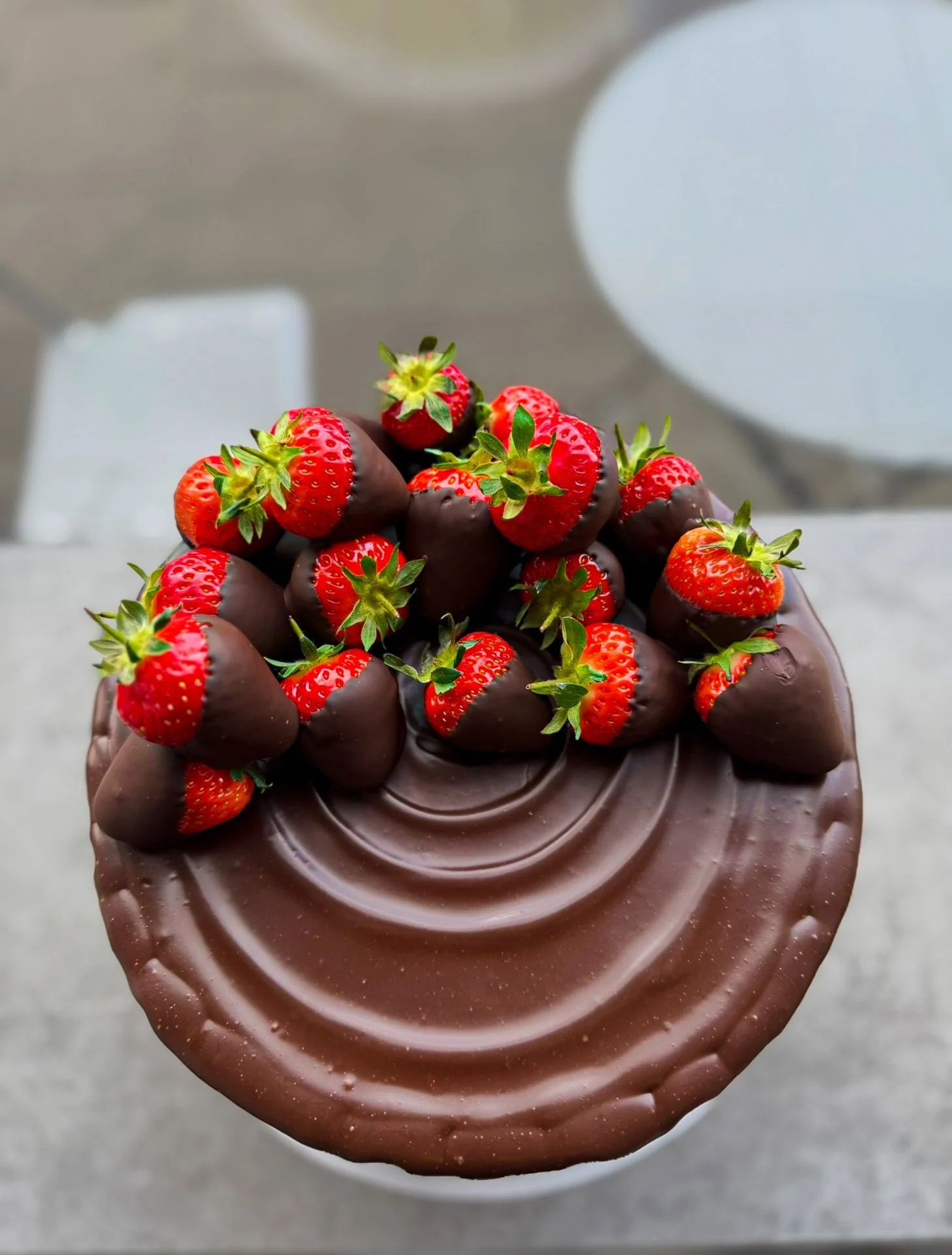 A chocolate-covered dessert topped with fresh strawberries.