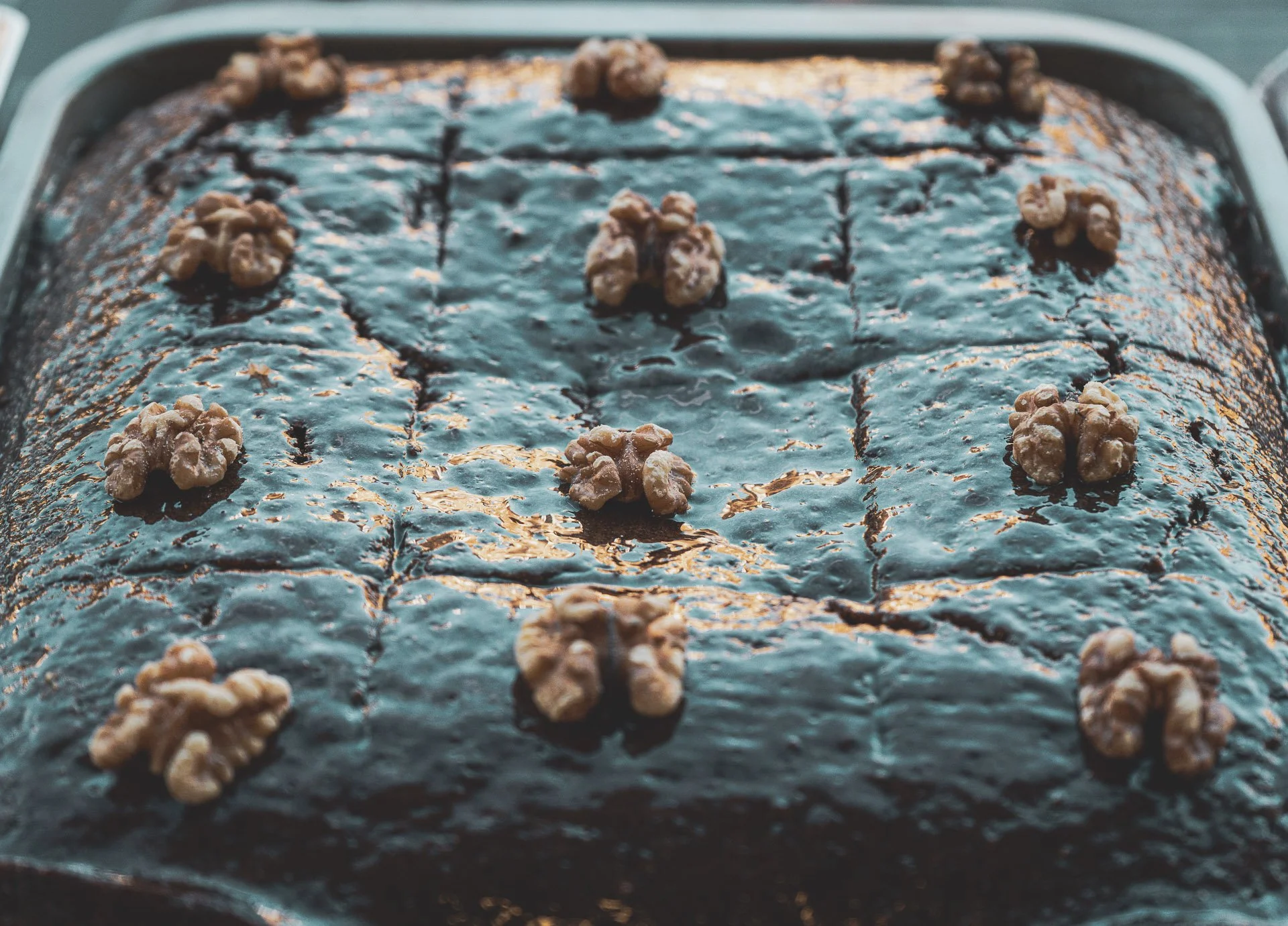 Chocolate cake with walnuts on top in a baking pan.
