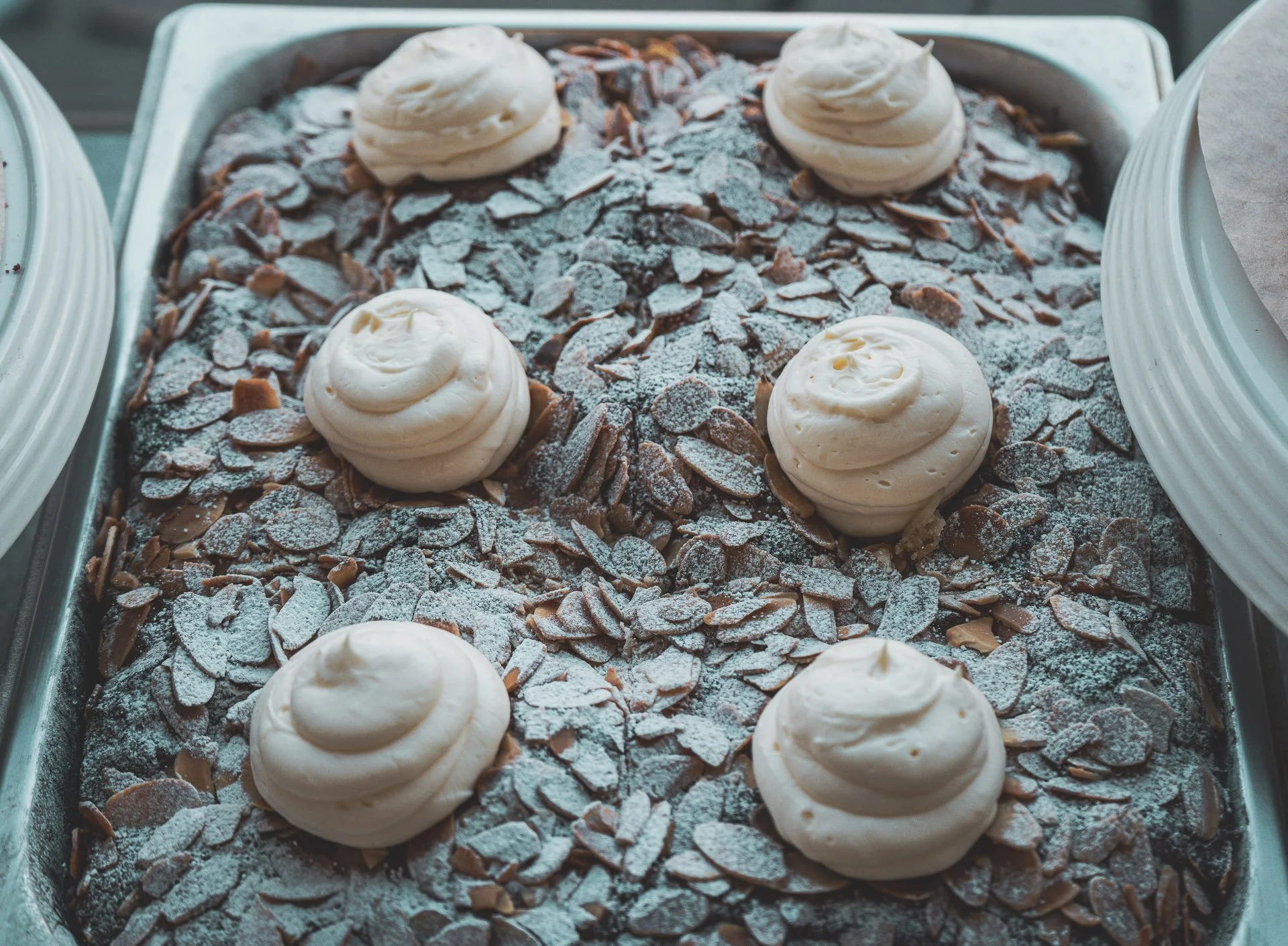 Baked chocolate dessert topped with powdered sugar and decorated with dollops of whipped cream.