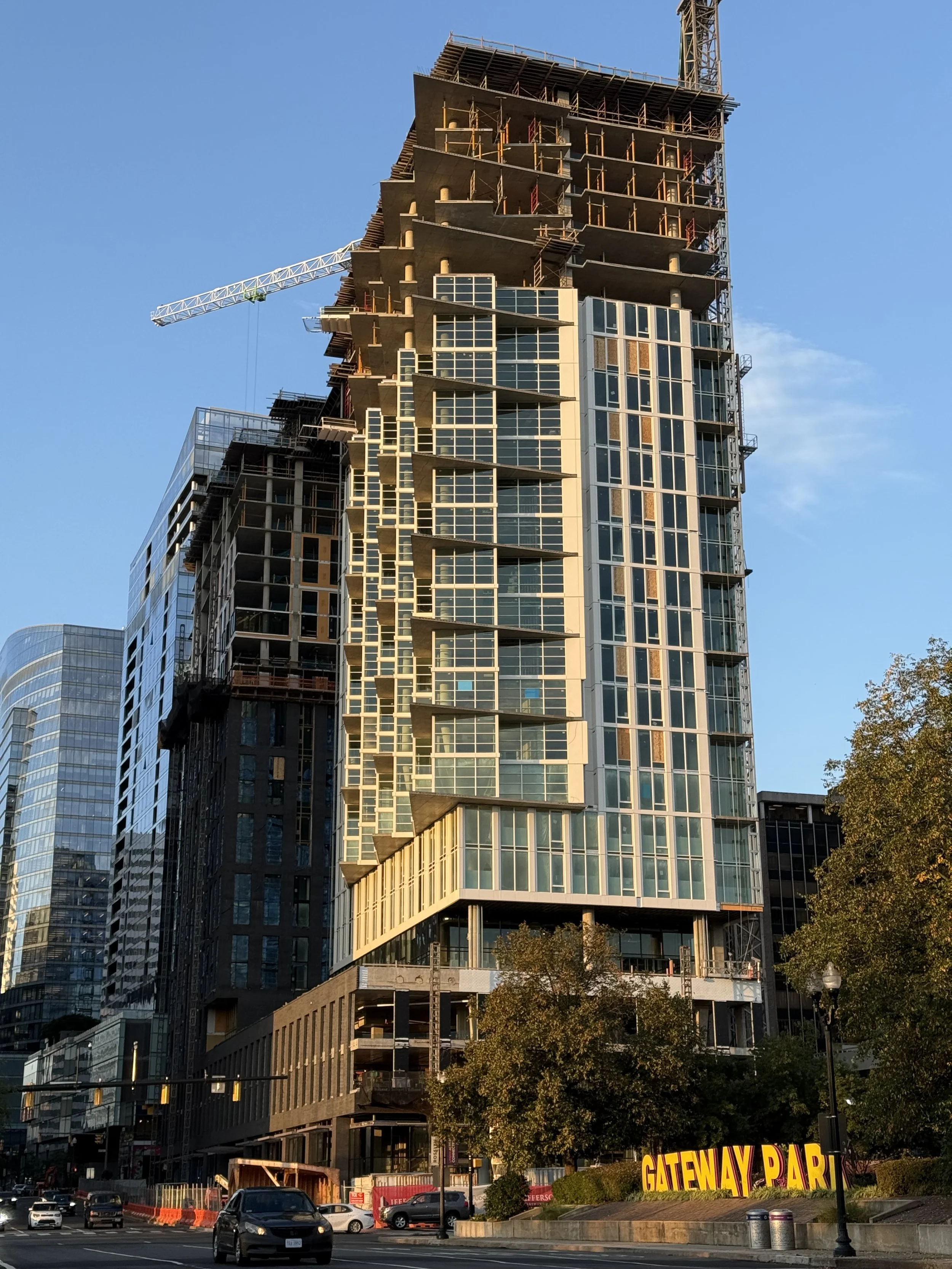 Under construction high-rise building with scaffolding and cranes in an urban area during the daytime.