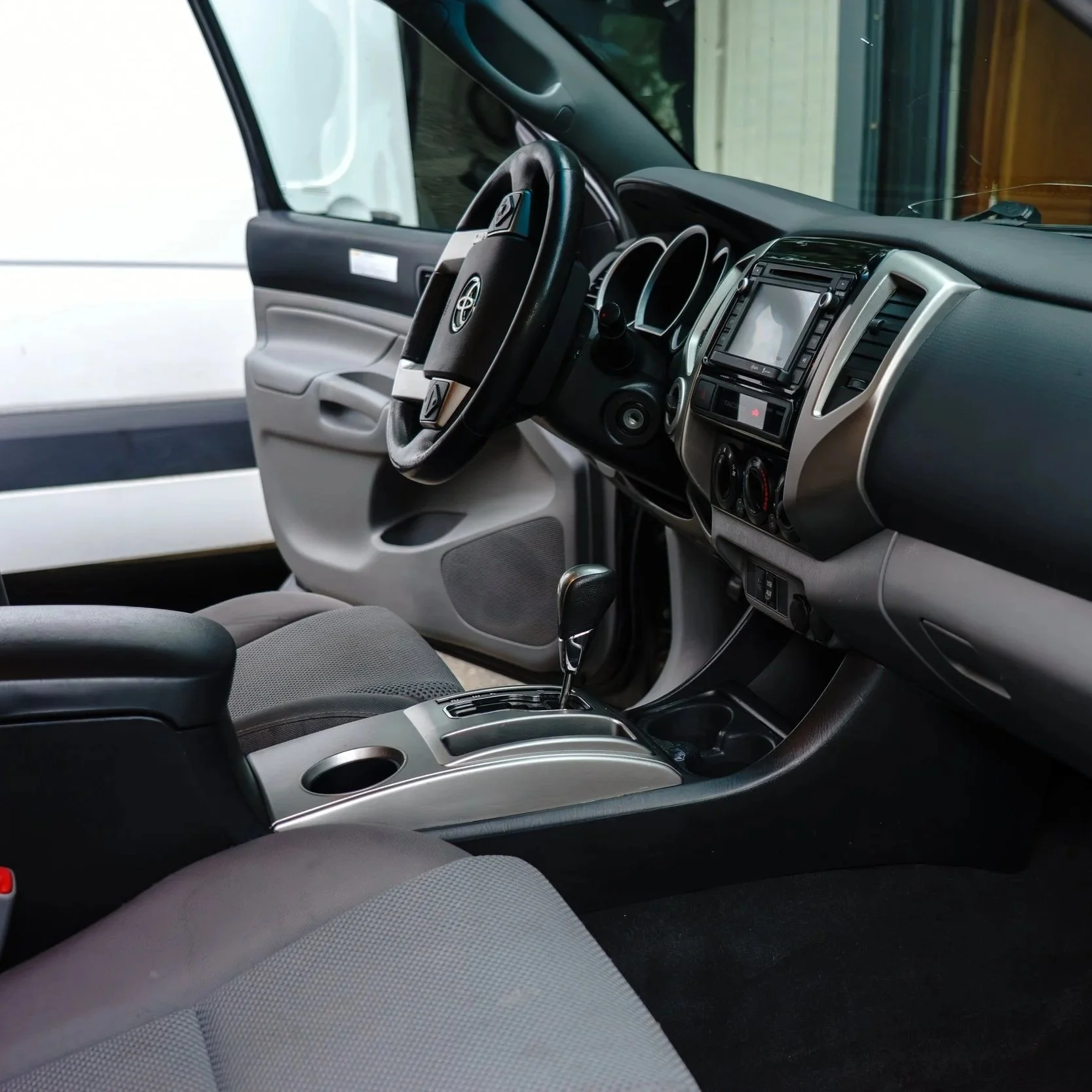 Interior view of a vehicle's dashboard, steering wheel, gear shift, and front seats.