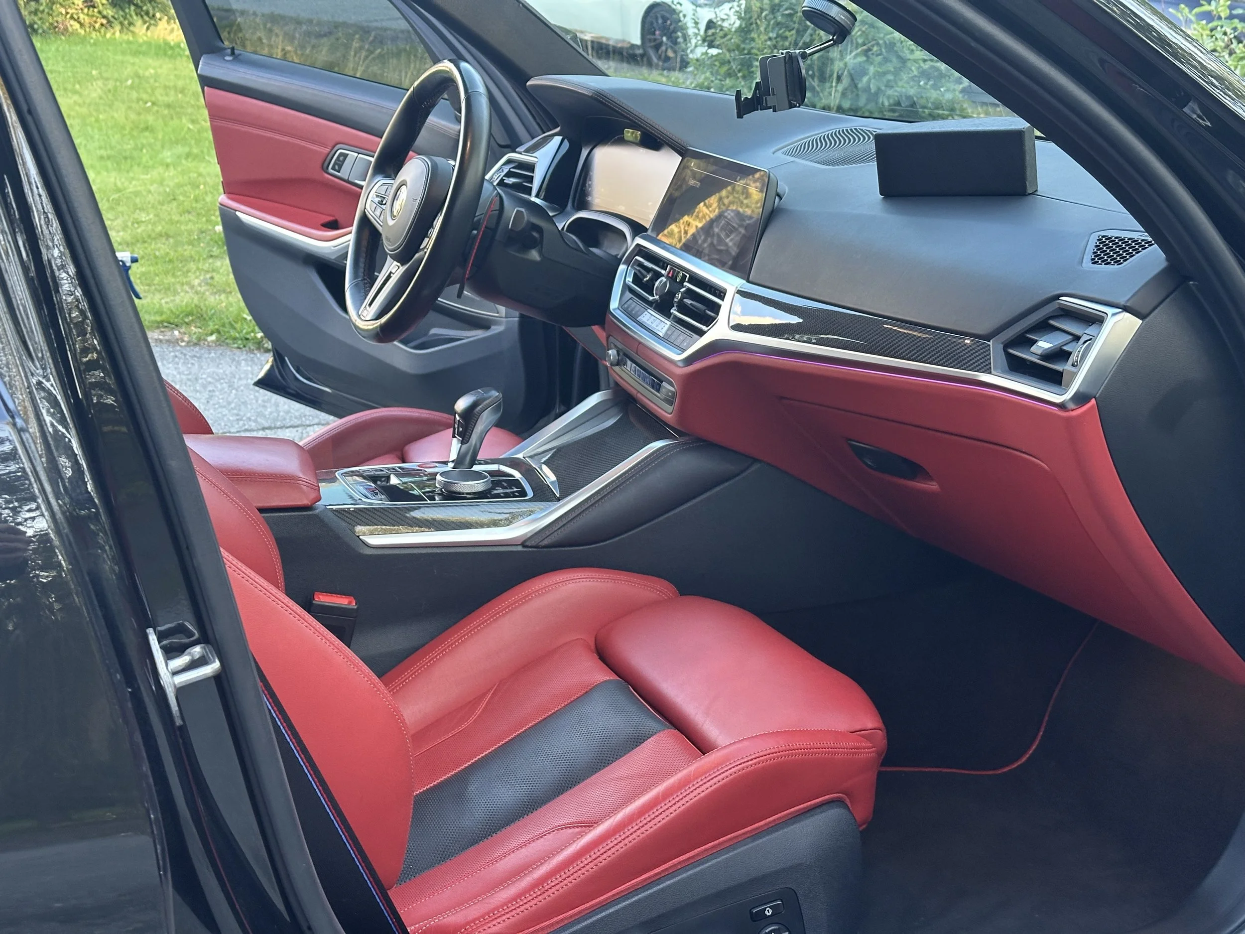 Interior of a modern car with red leather seats, a black dashboard, a large touchscreen display, and a gear shifter on the center console.