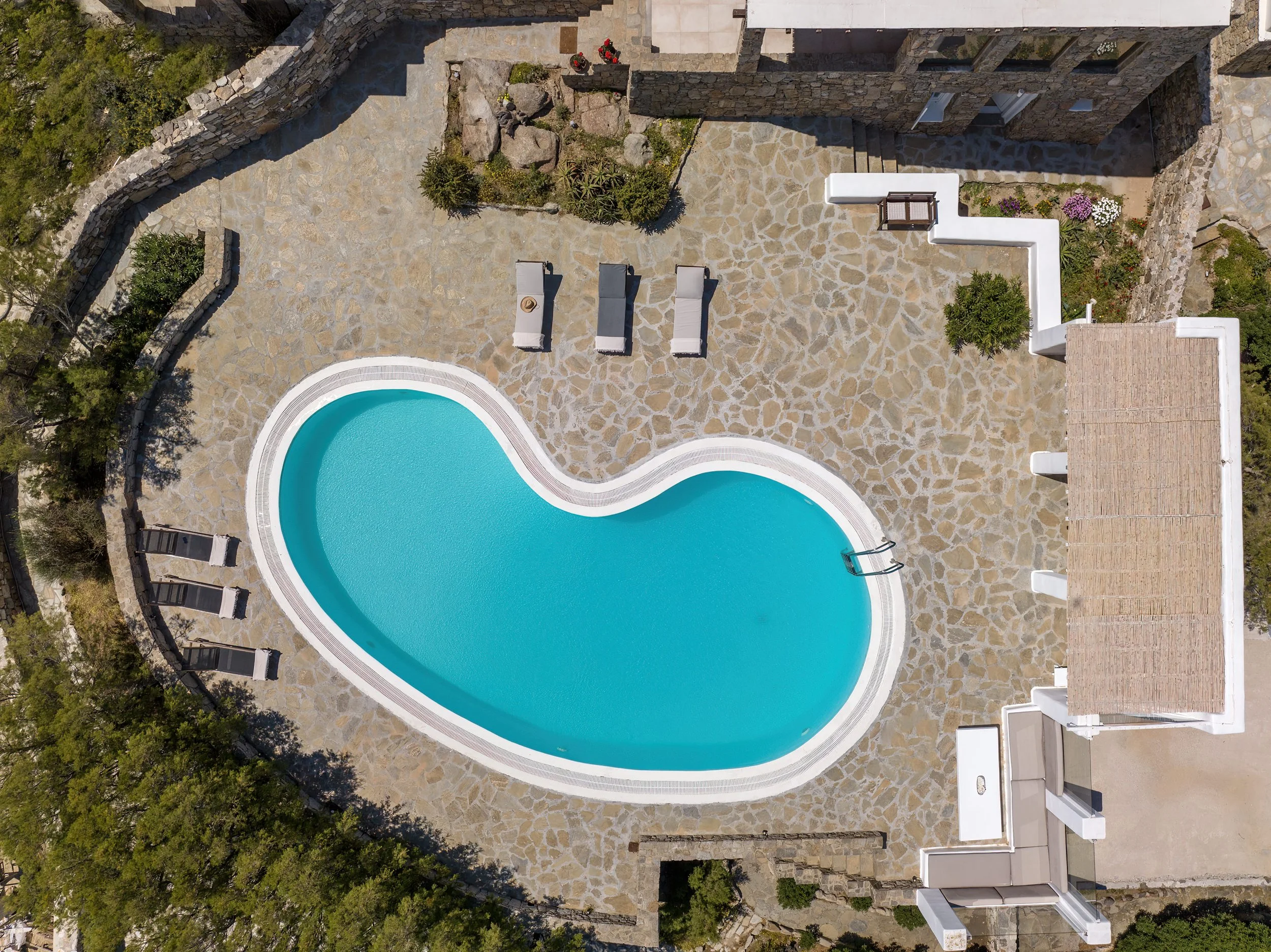 Top-down view of the private pool and terrace layout with sun loungers, and a covered seating pavilion, Villa Zanetti Mykonos.