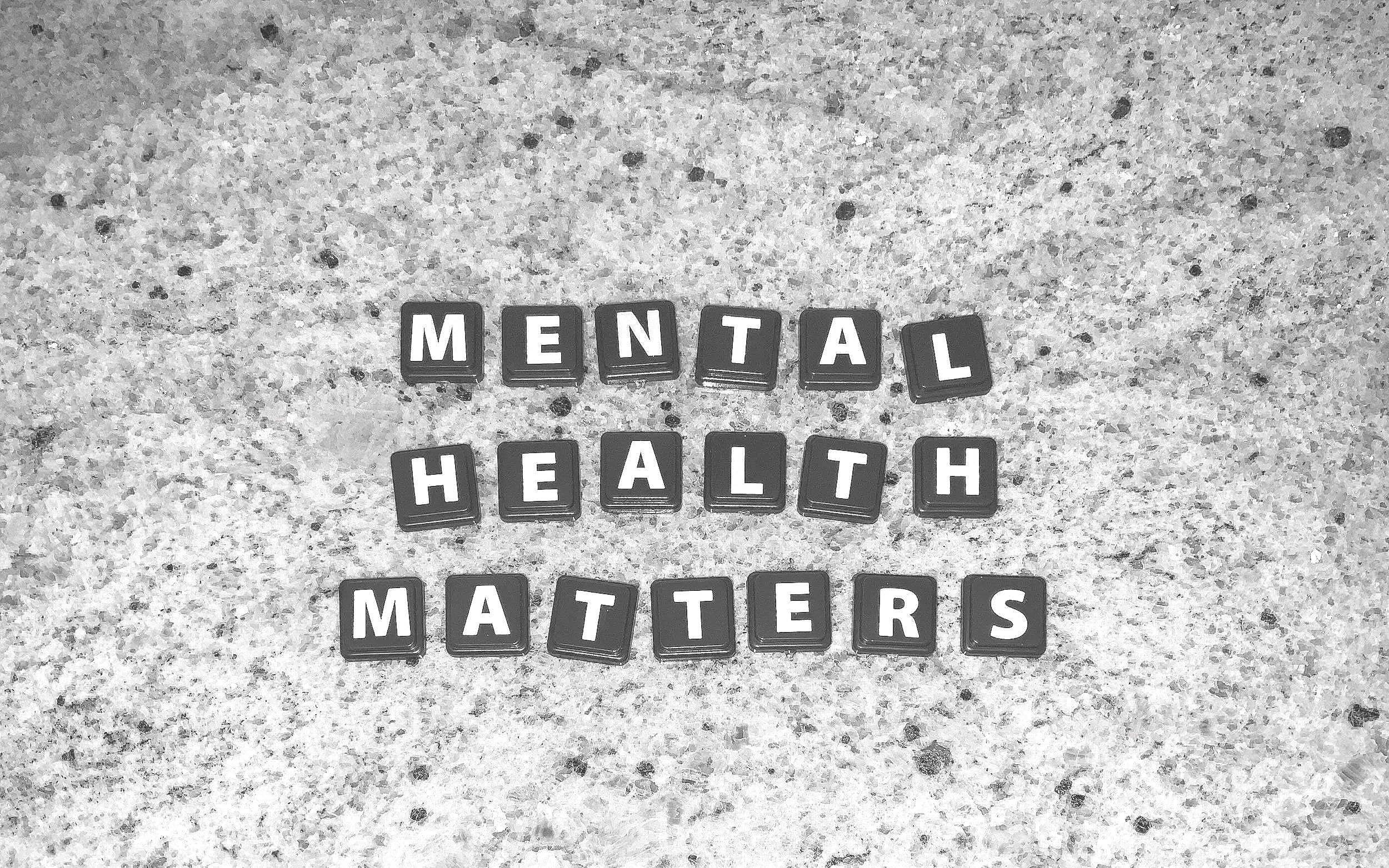 Black letter tiles spelling out "YOUR MENTAL HEALTH MATTERS" on a speckled surface.