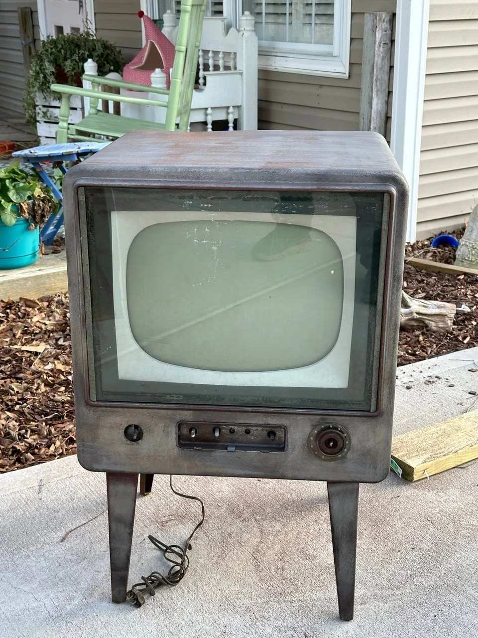 Vintage CRT television set with a rounded screen, clean and restored metallic body, wooden legs, and control knobs on the front after being cleaned and restored with a laser.