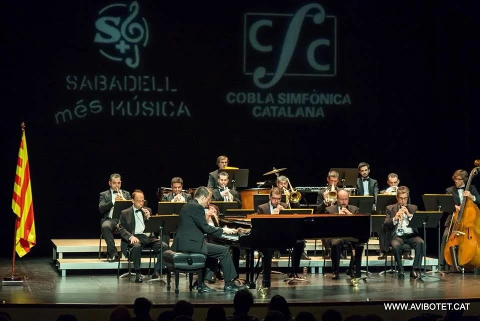Cobla Sinfónica Catalana in the background, with Gerard Pastor playing the piano just in front during a concert.