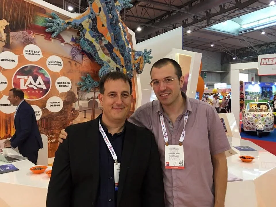 Heiko Kraft and Gerard Pastor posing for a photo with a stand in the background at a trade fair.