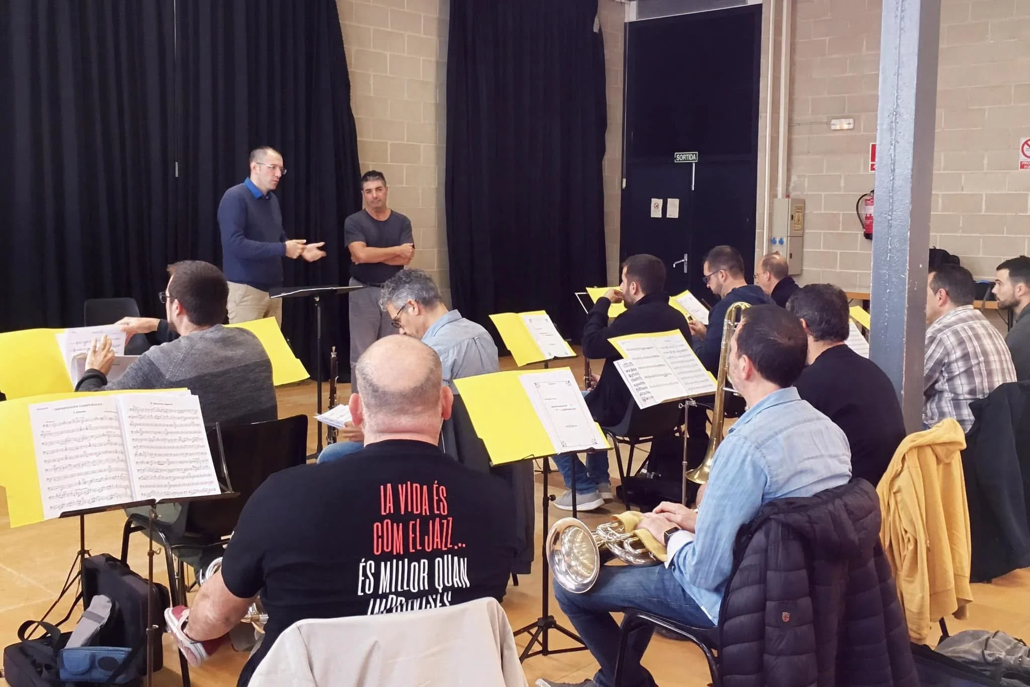 Rehearsal of the Cobla Sinfónica Catalana, with Gerard Pastor speaking to the musicians and composer Paulí Peña beside him.