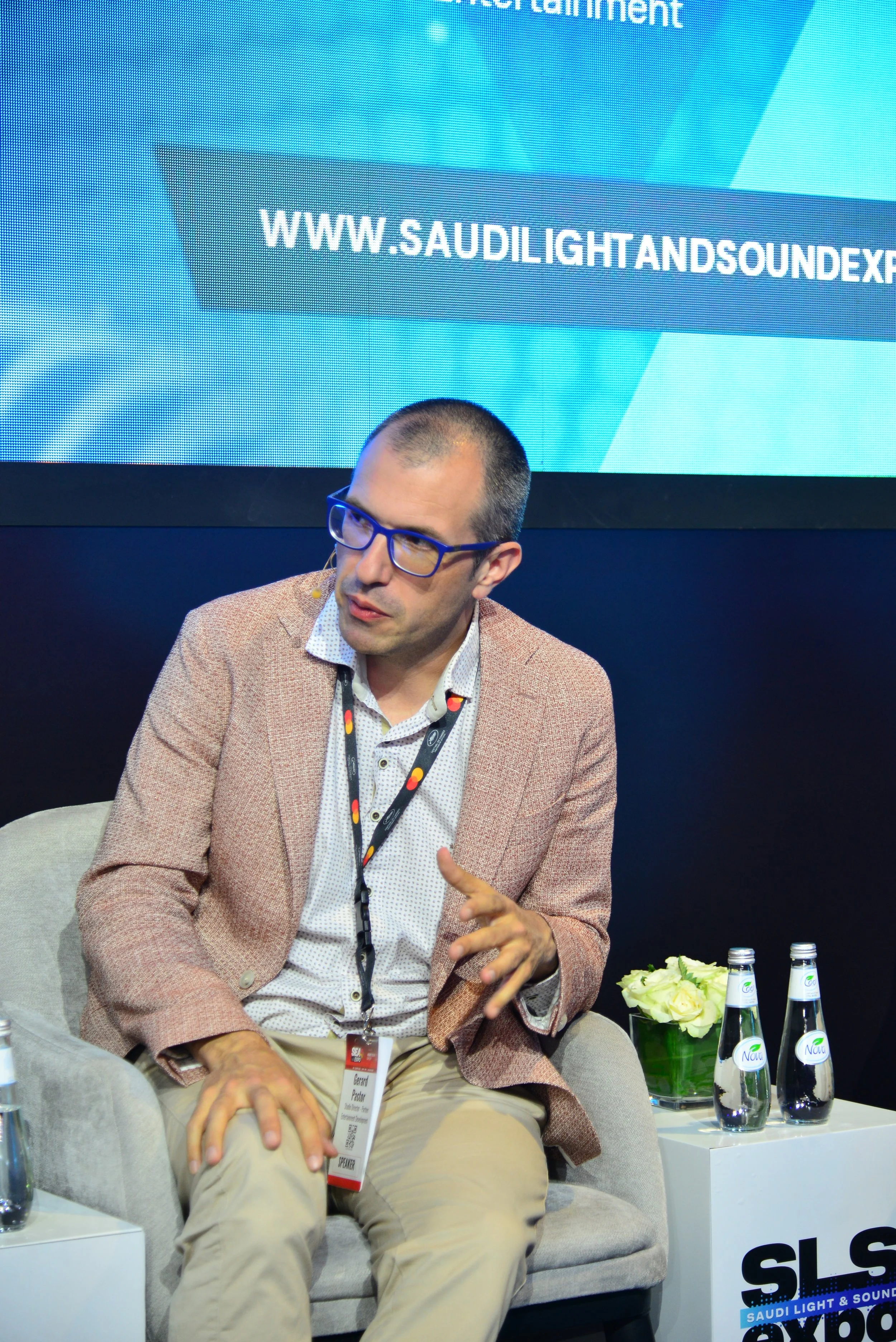 Gerard Pastor seated on a conference stage, chatting.