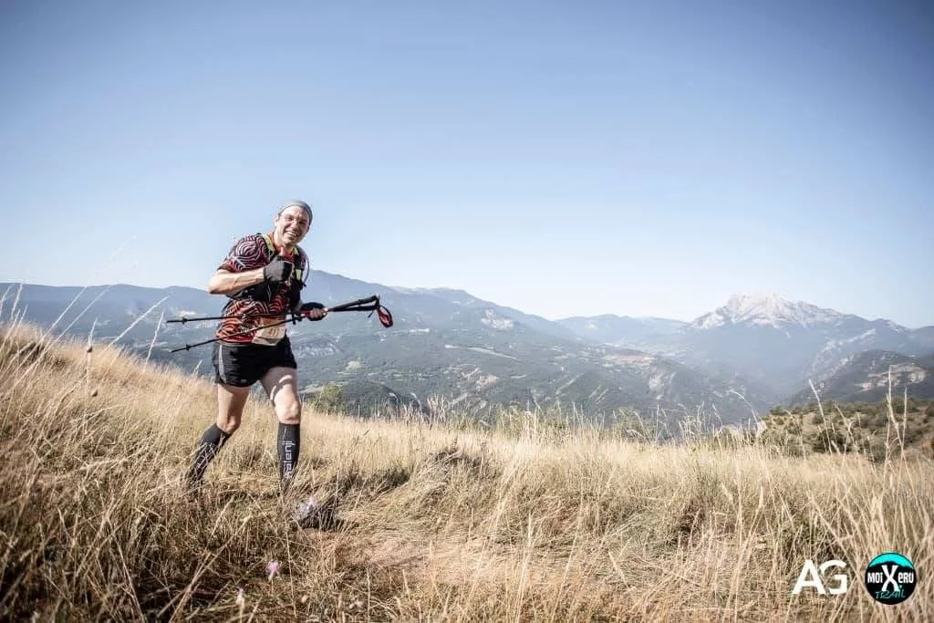 Gerard Pastor running a trail race, smiling and giving a thumbs-up to the camera.