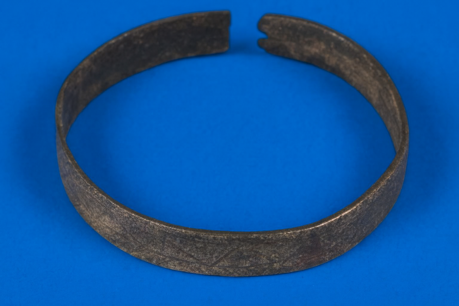 A metal circular object with a gap, resting on a blue background.