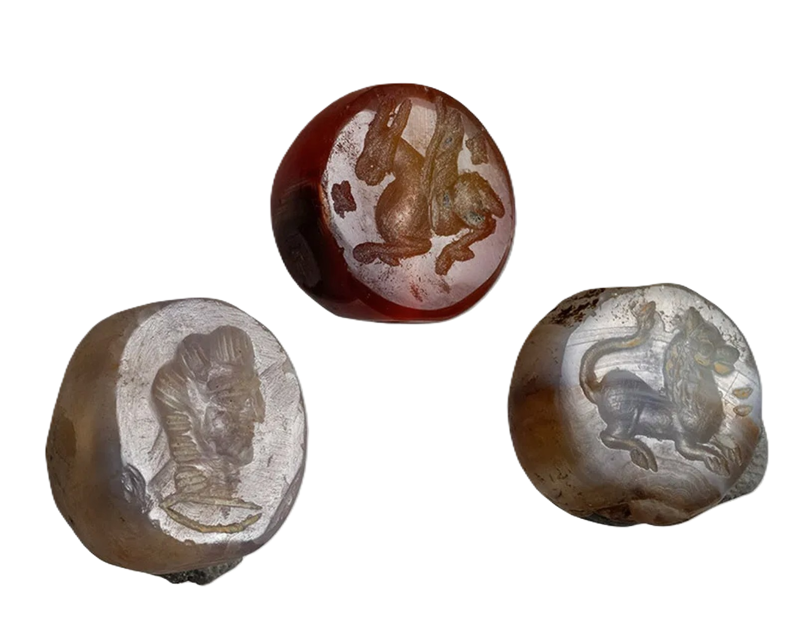 Three carved stone balls featuring intricate animal and human face designs, set against a black background.