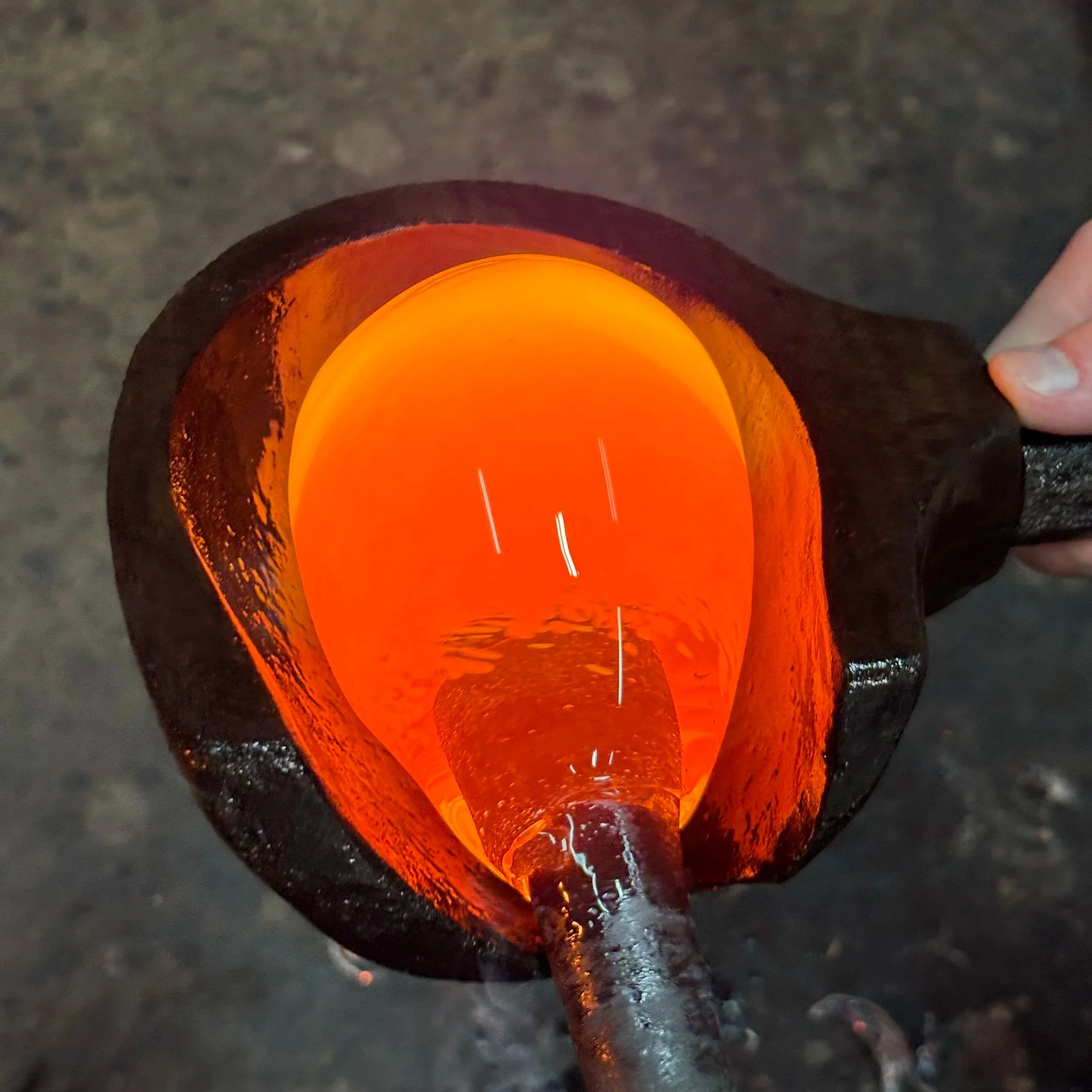 A glowing orange hot metal being poured from a large crucible.