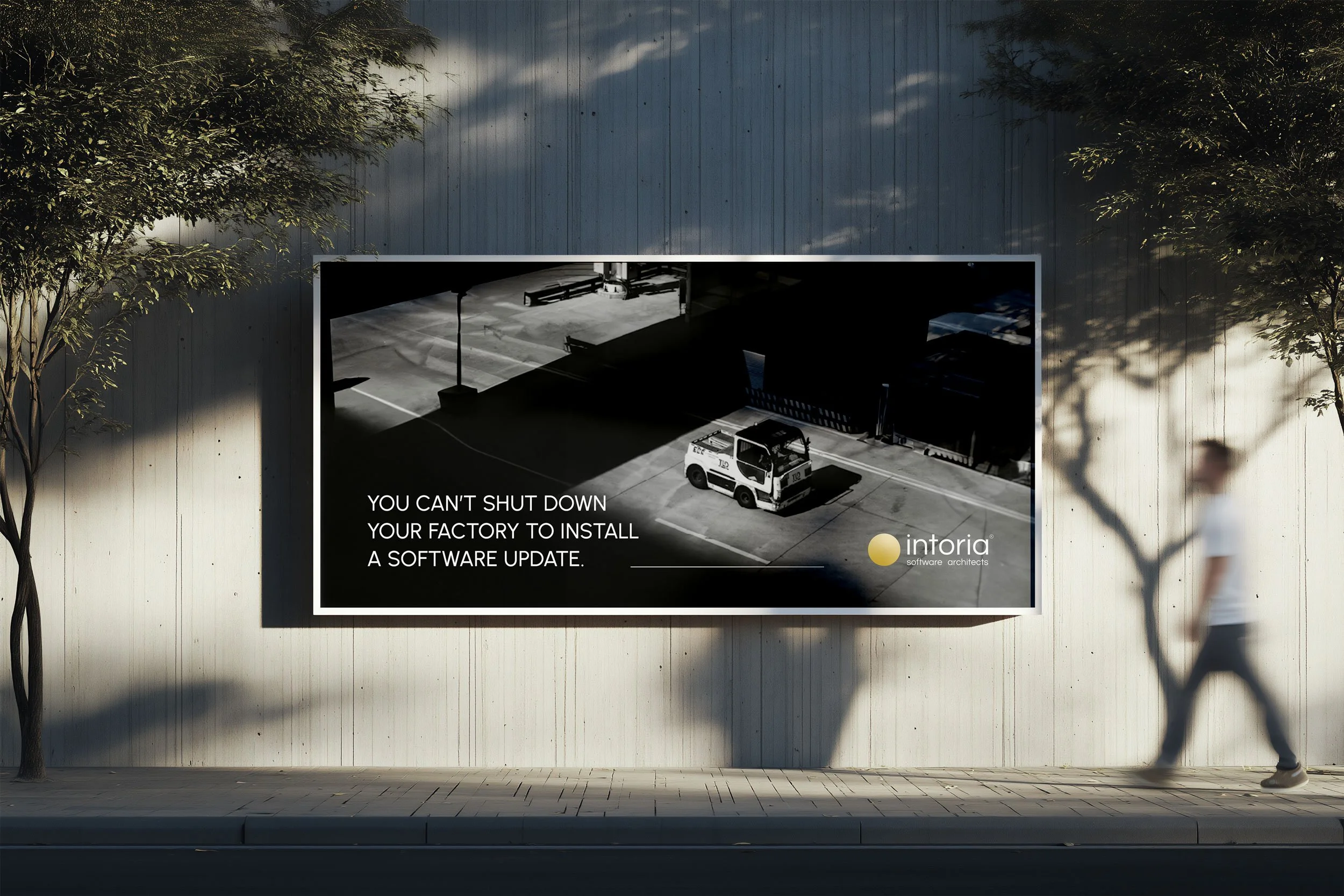 Billboard on a wall with a black and white photo of a delivery truck and the message: 'You can't shut down your factory to install a software update,' with the logo of Intoria software architects.