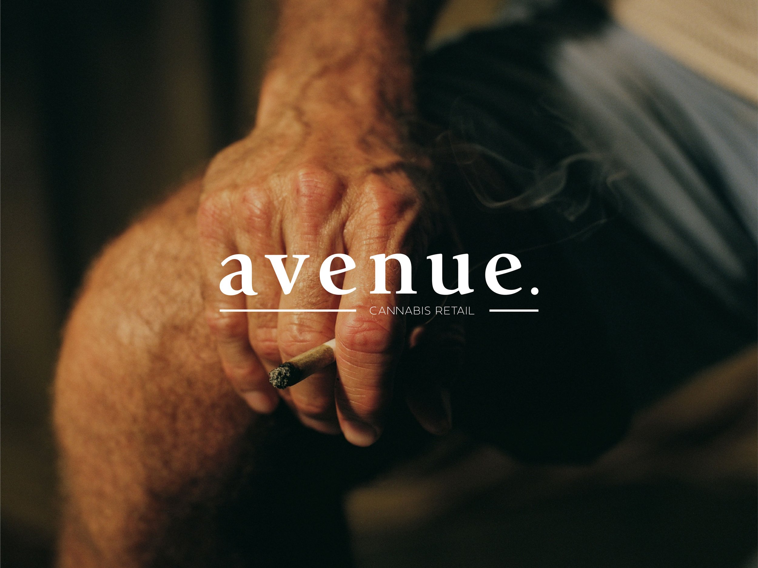 Close-up of a person’s hand holding a lit joint with smoke rising from it, with the word 'avenue' overlaid on the image and the words 'CANNABIS RETAIL' beneath.