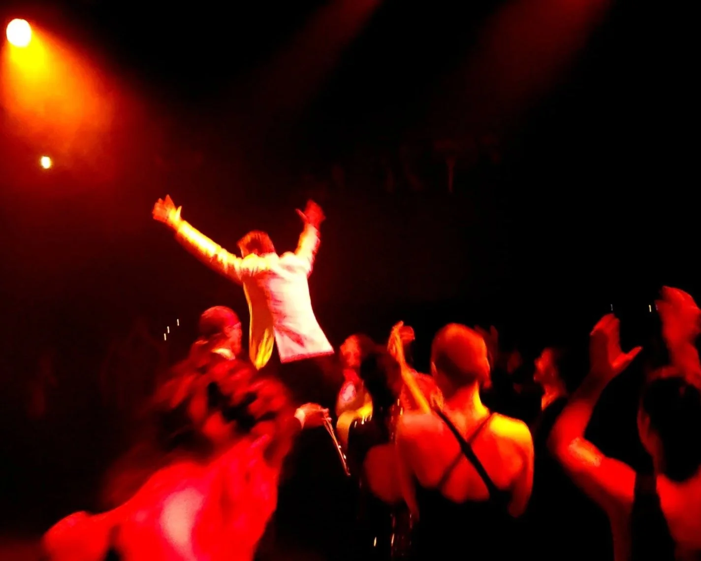 People dancing at a nightclub with colorful stage lights.