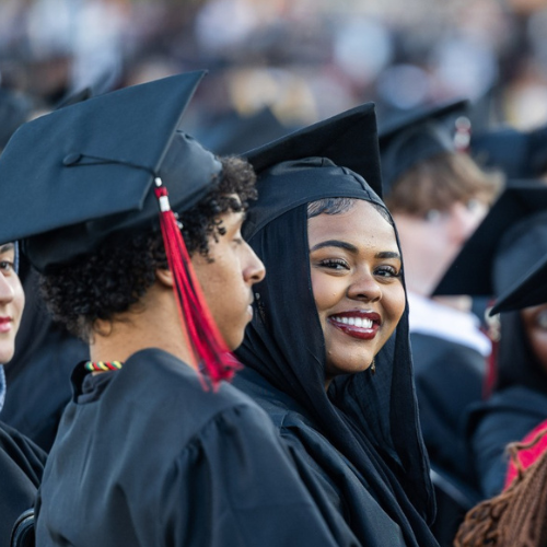 Group of graduates in caps and gowns at graduation ceremony, celebrating achievement.