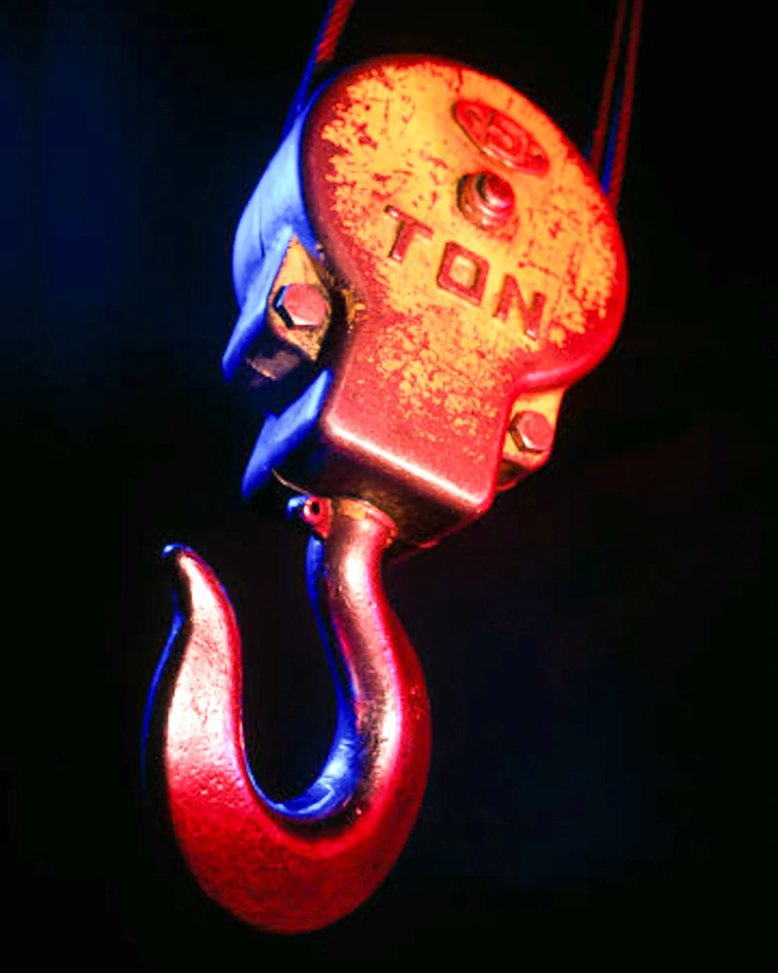 Close-up of a heavy-duty lifting hook photographed against a dark background.
